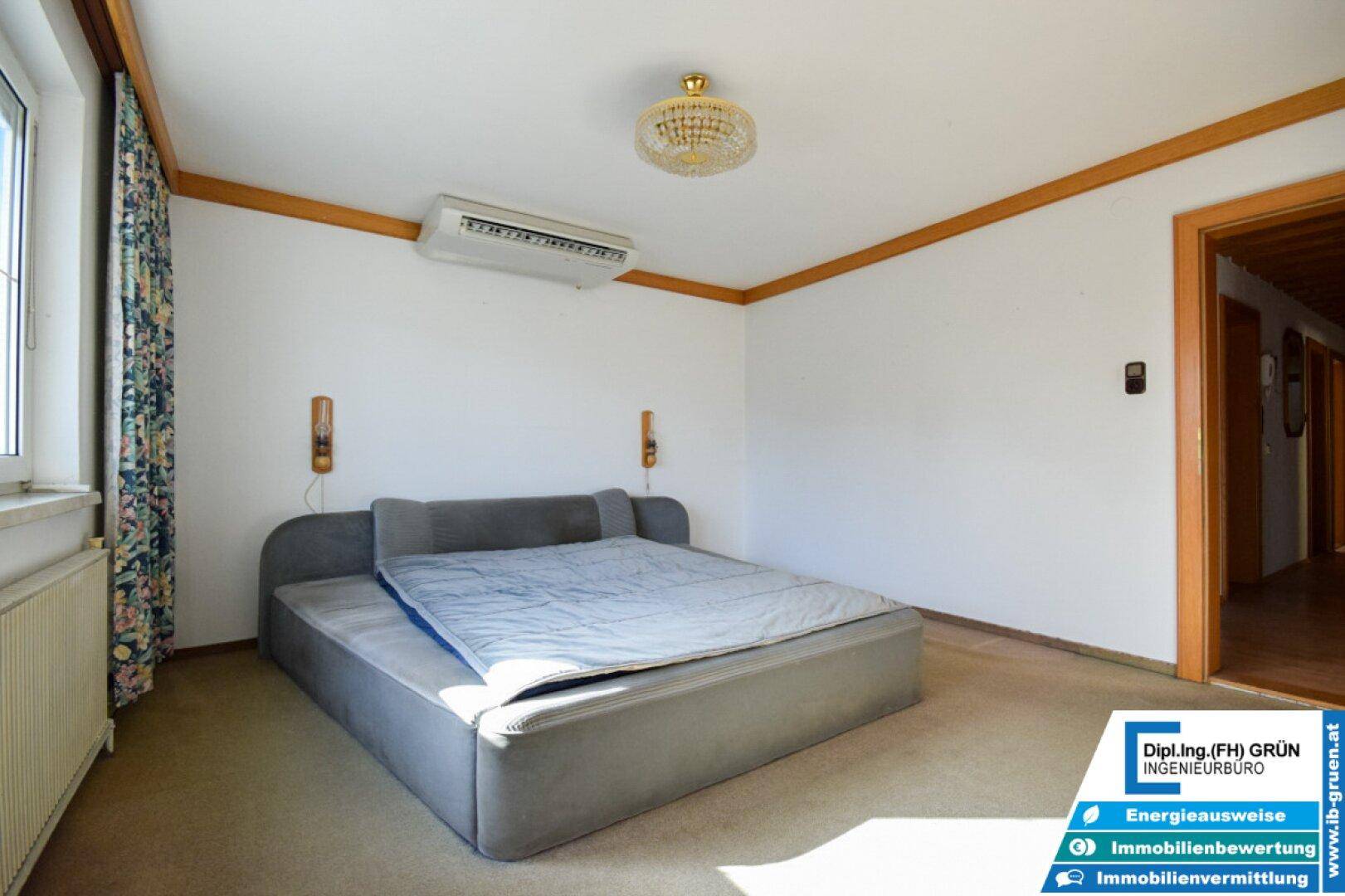 Schlafzimmer mit Teppichboden, großem Bett und Klimaanlage an der Decke.