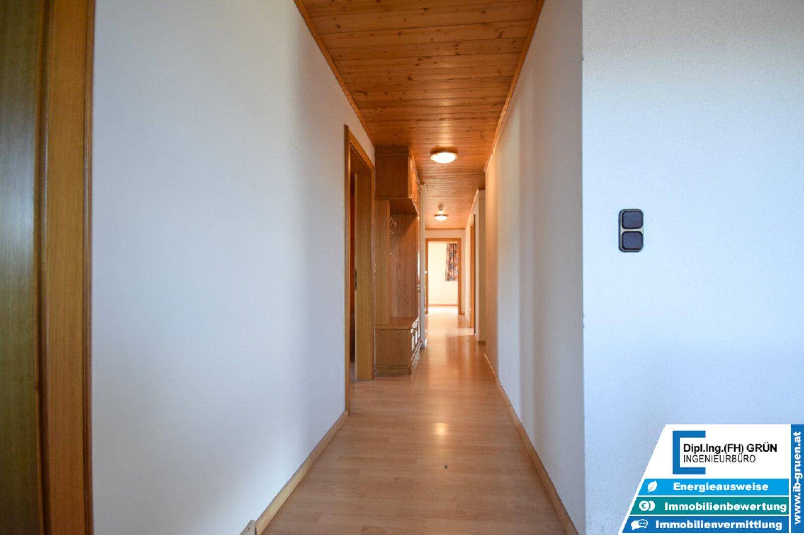 Heller Flur mit Holzboden und Holzdecke, führt zu weiteren Räumen.