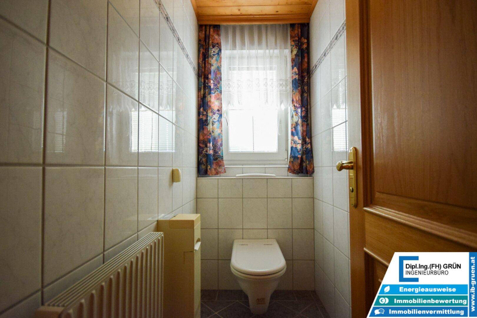 Separates WC mit Toilette, Heizkörper und Fenster, einfach und funktional.