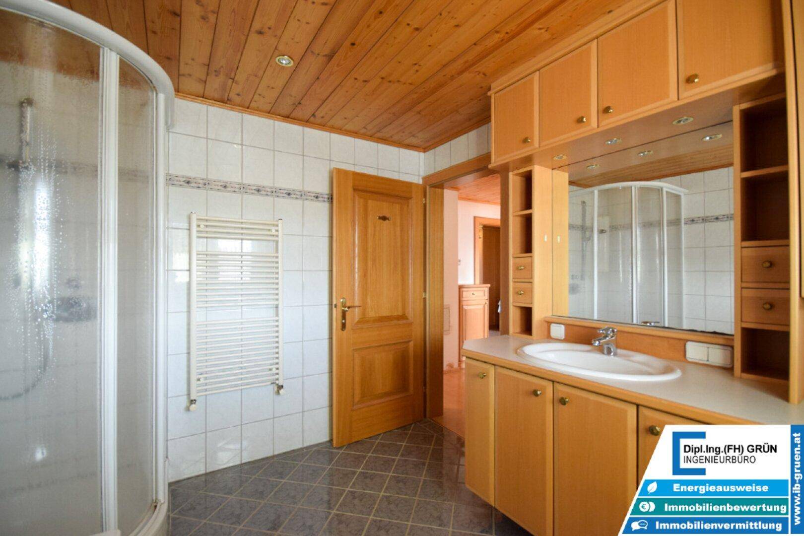 Badezimmer mit beheiztem Handtuchhalter, großem Spiegel und Holzdecke.