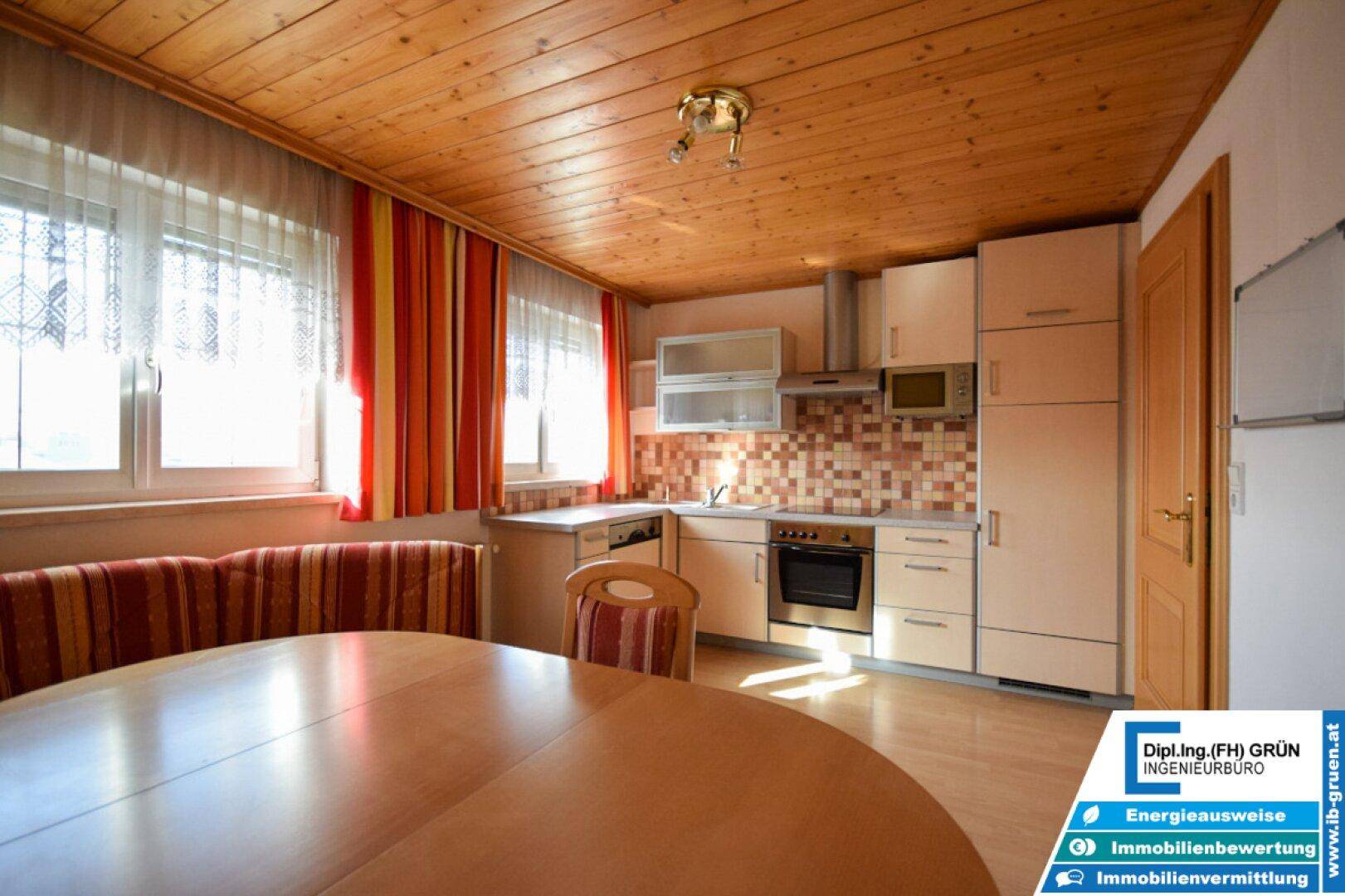 Funktionale Küche mit Holzdecke, Einbauschränken und Essbereich.