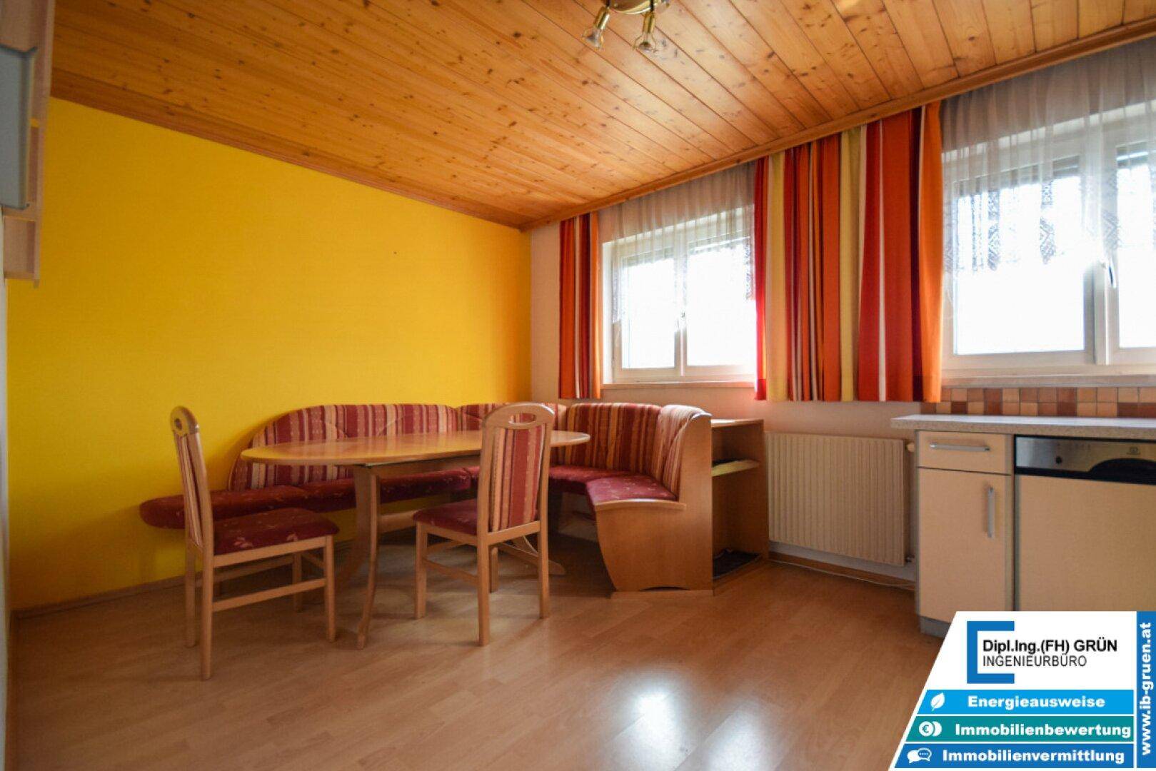 Gemütliche Essküche mit Holzbalkendecke, gelben Wänden und integrierter Sitzecke.