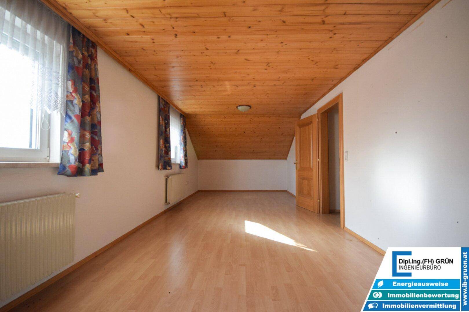 Leerer Raum mit Dachschräge, Holzdecke und Laminatboden.