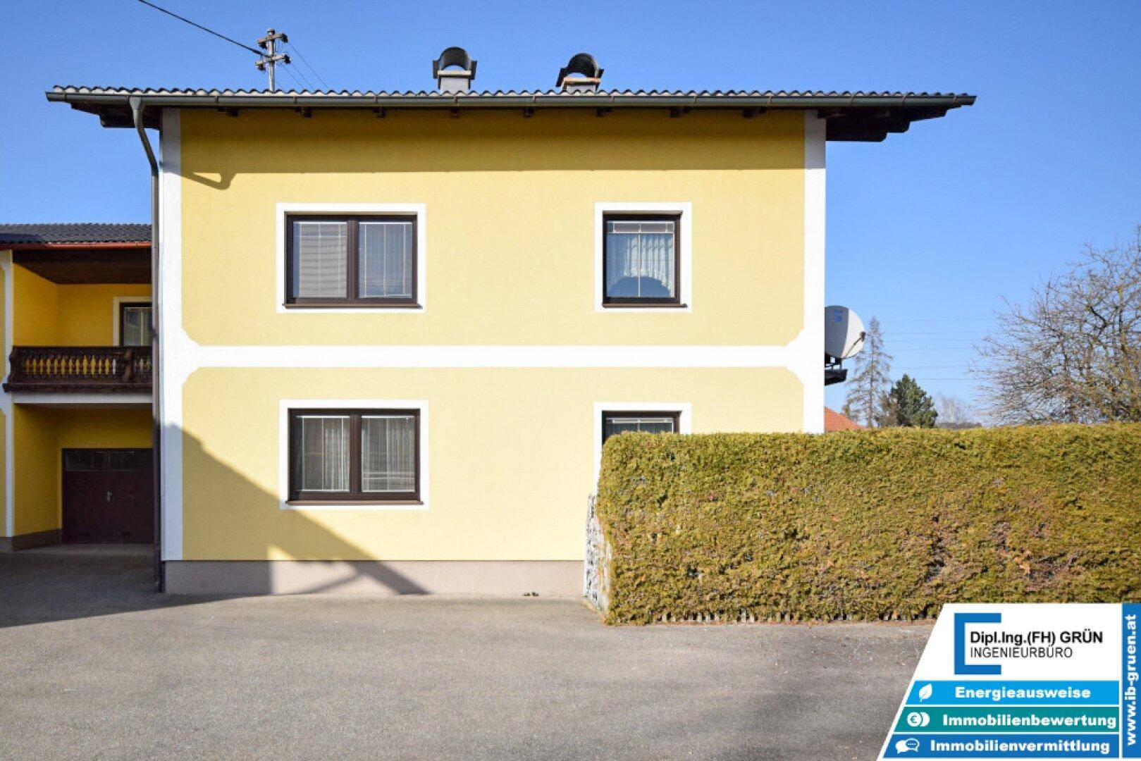 Seitenansicht des gelben Hauses mit gepflegter Hecke und Vorgarten.