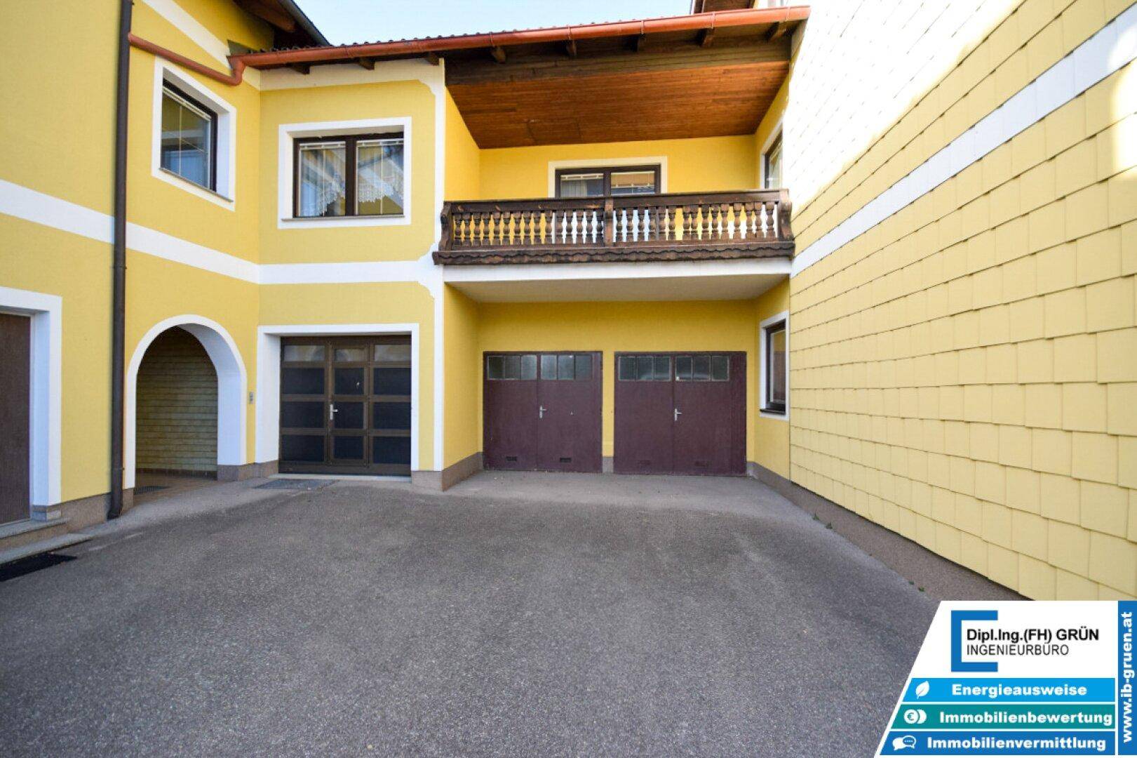 Gelbes Haus mit Doppelgarage und traditionellem Holzbalkon.