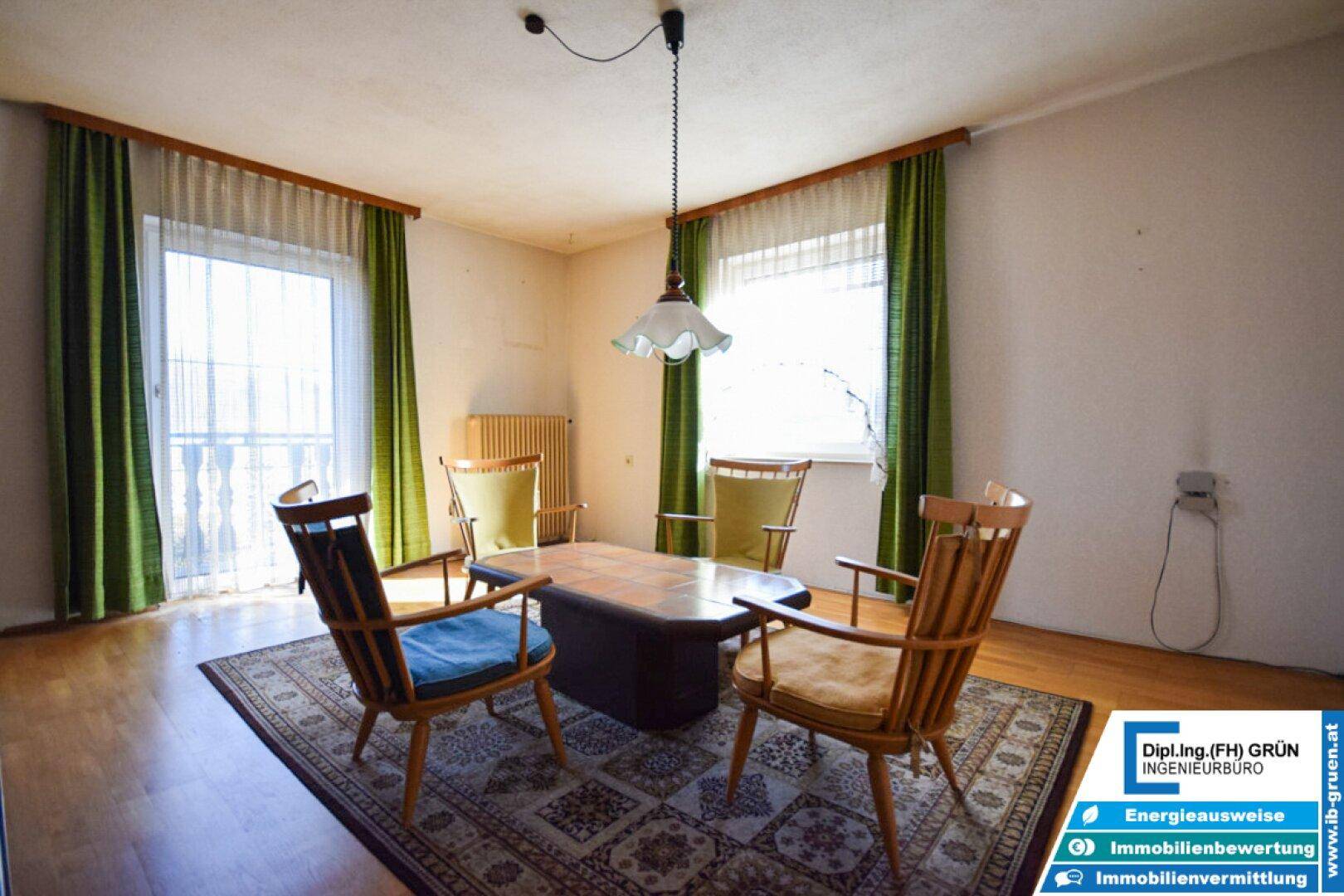 Wohnzimmer mit Vintage-Möbeln, Teppich und Zugang zum Balkon.