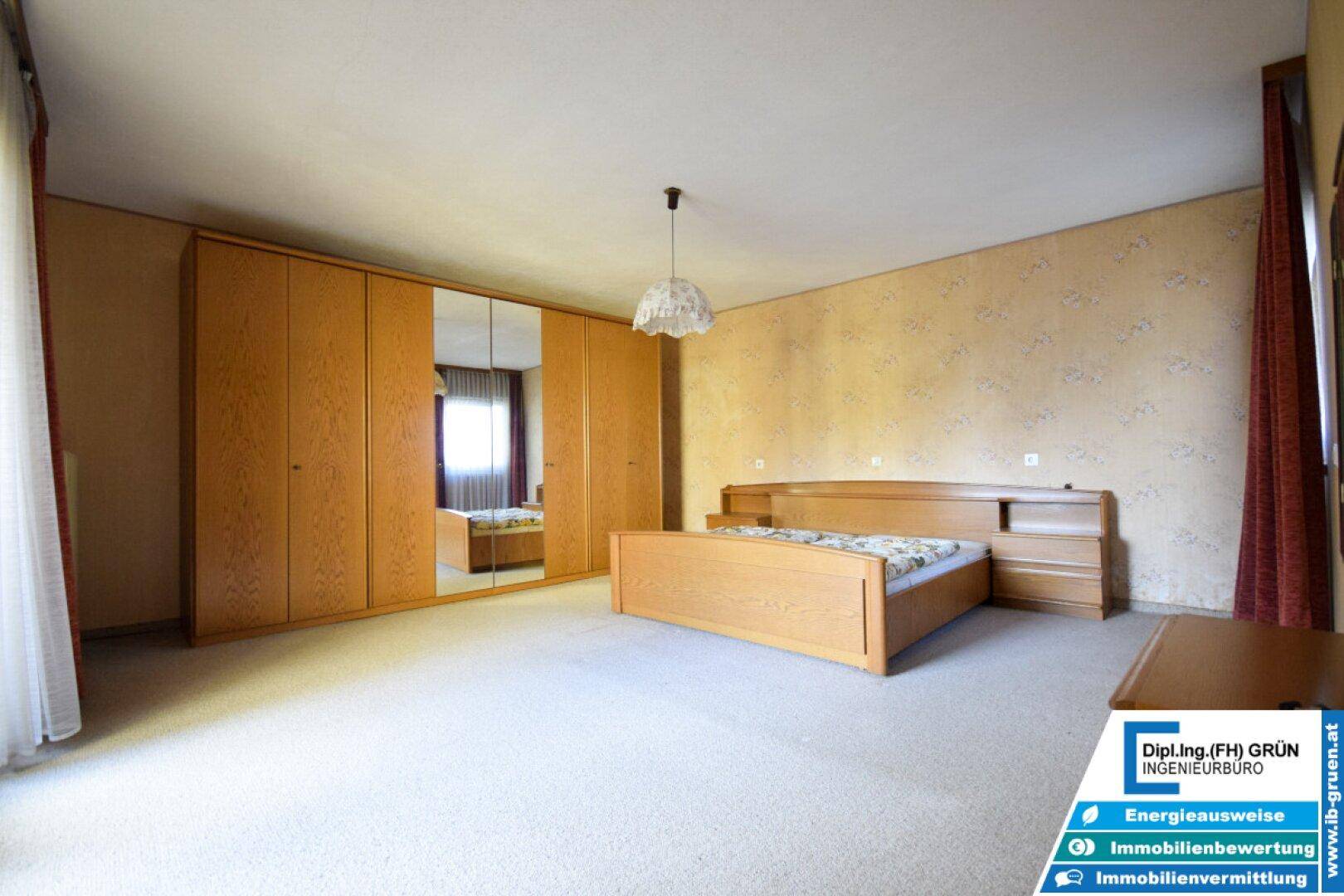 Geräumiges Schlafzimmer mit Doppelbett, großem Kleiderschrank und Teppichboden.