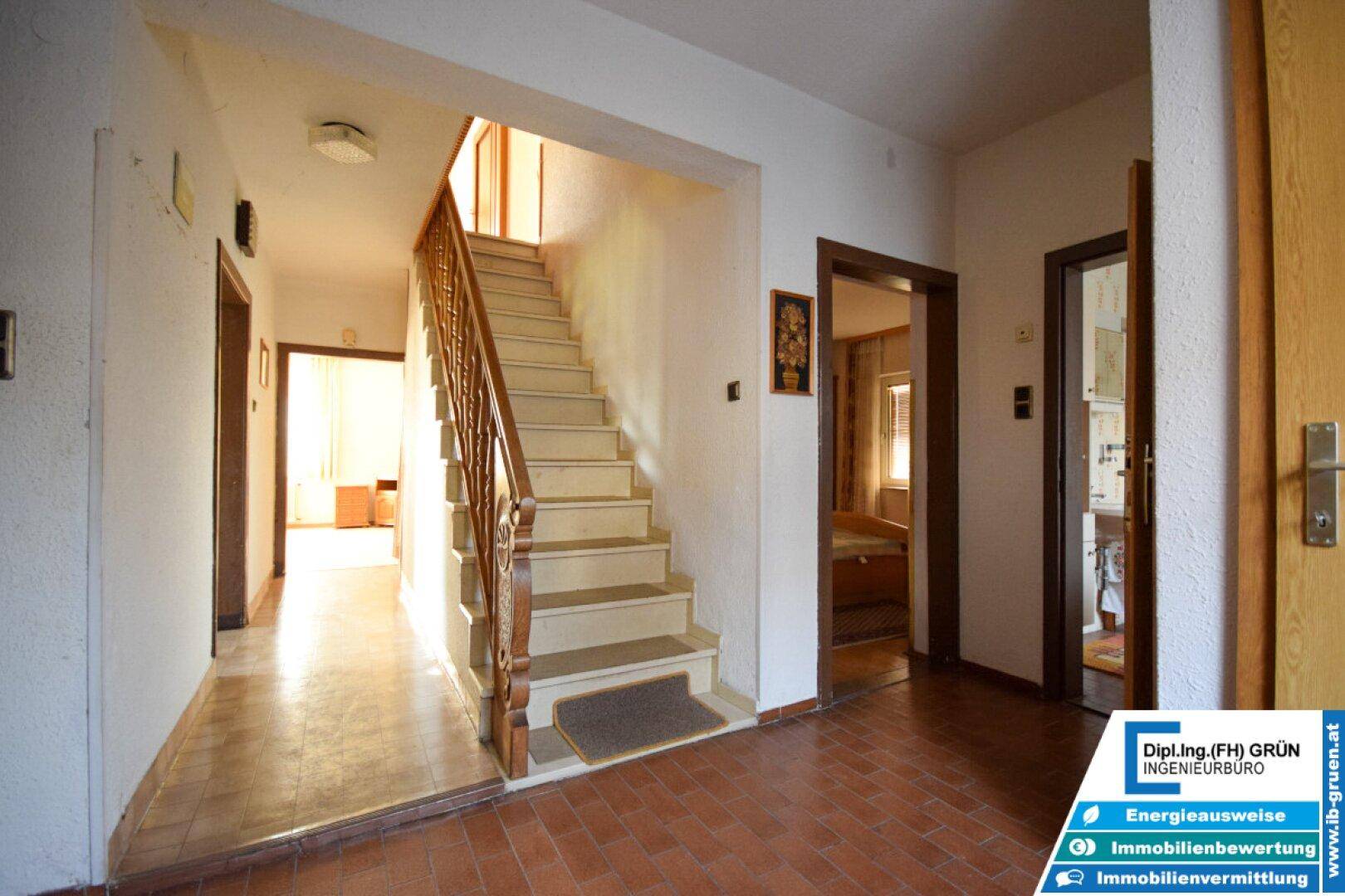 Heller Flur mit Treppe, Fliesenboden und Holzelementen.