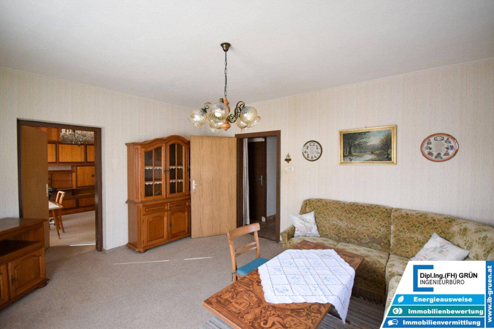 Gemütliches Wohnzimmer mit Sofa, Holzschrank und Teppichboden.