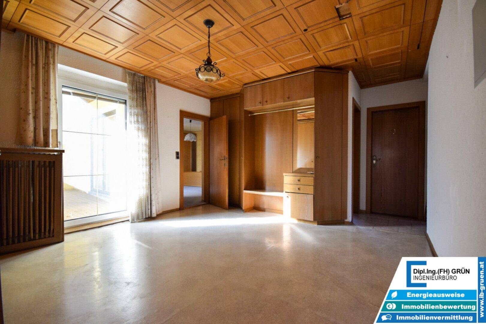 Geräumiger Raum mit Holzdeckenverkleidung, Einbauschrank und Zugang zum Balkon.