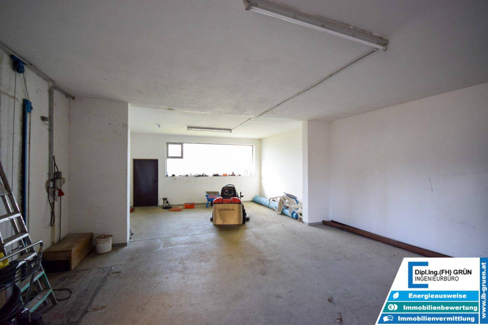 Großer, leerer Raum, möglicherweise eine Garage oder Werkstatt, mit Fenster.