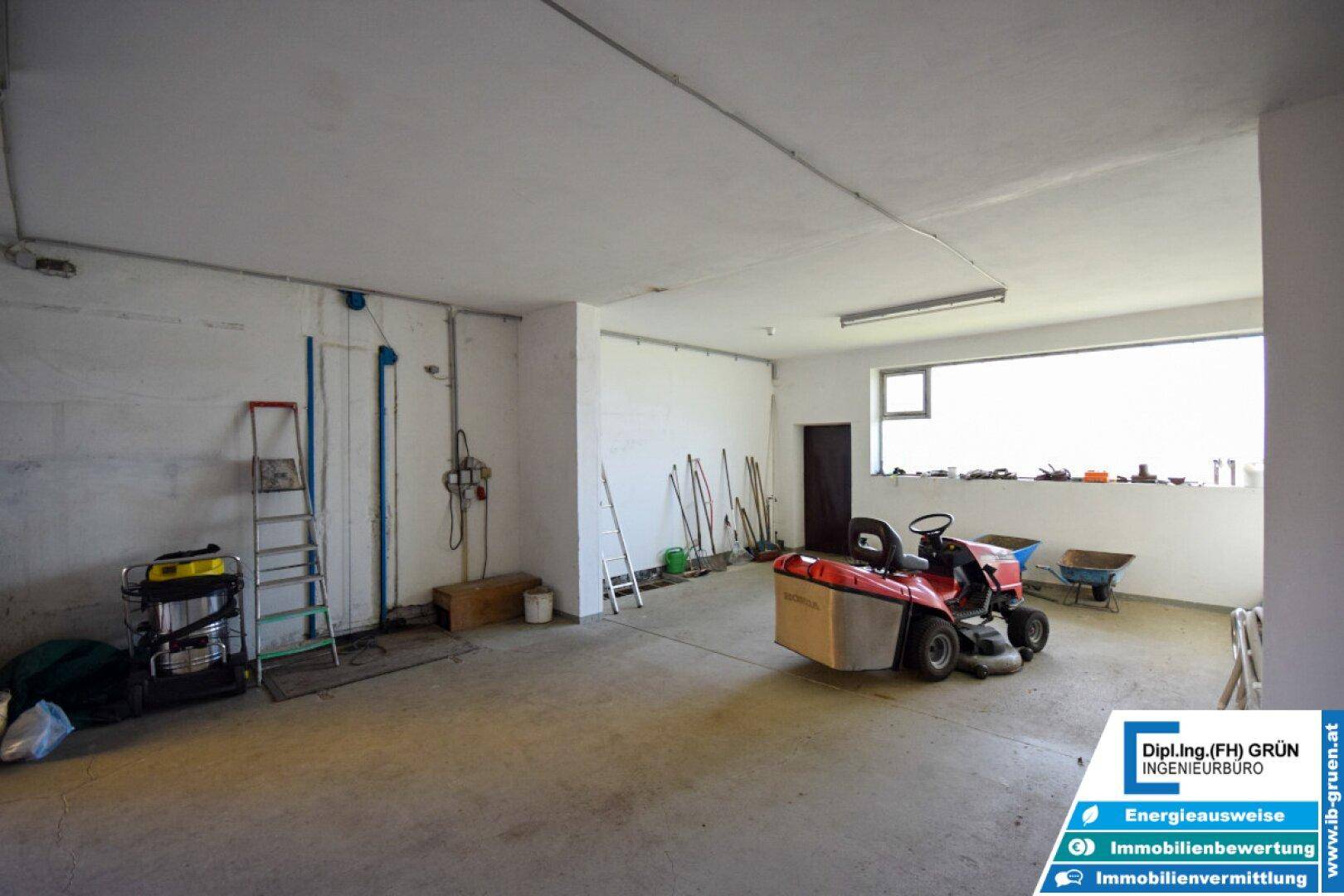 Großer, heller Garagen- oder Lagerraum mit Betonboden und verschiedenen Werkzeugen.