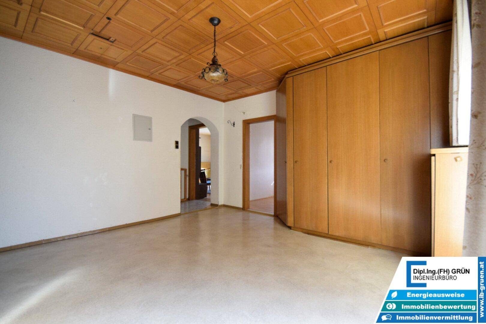 Raum mit Holzdeckenverkleidung, großem Einbauschrank und Zugang zu weiteren Zimmern.
