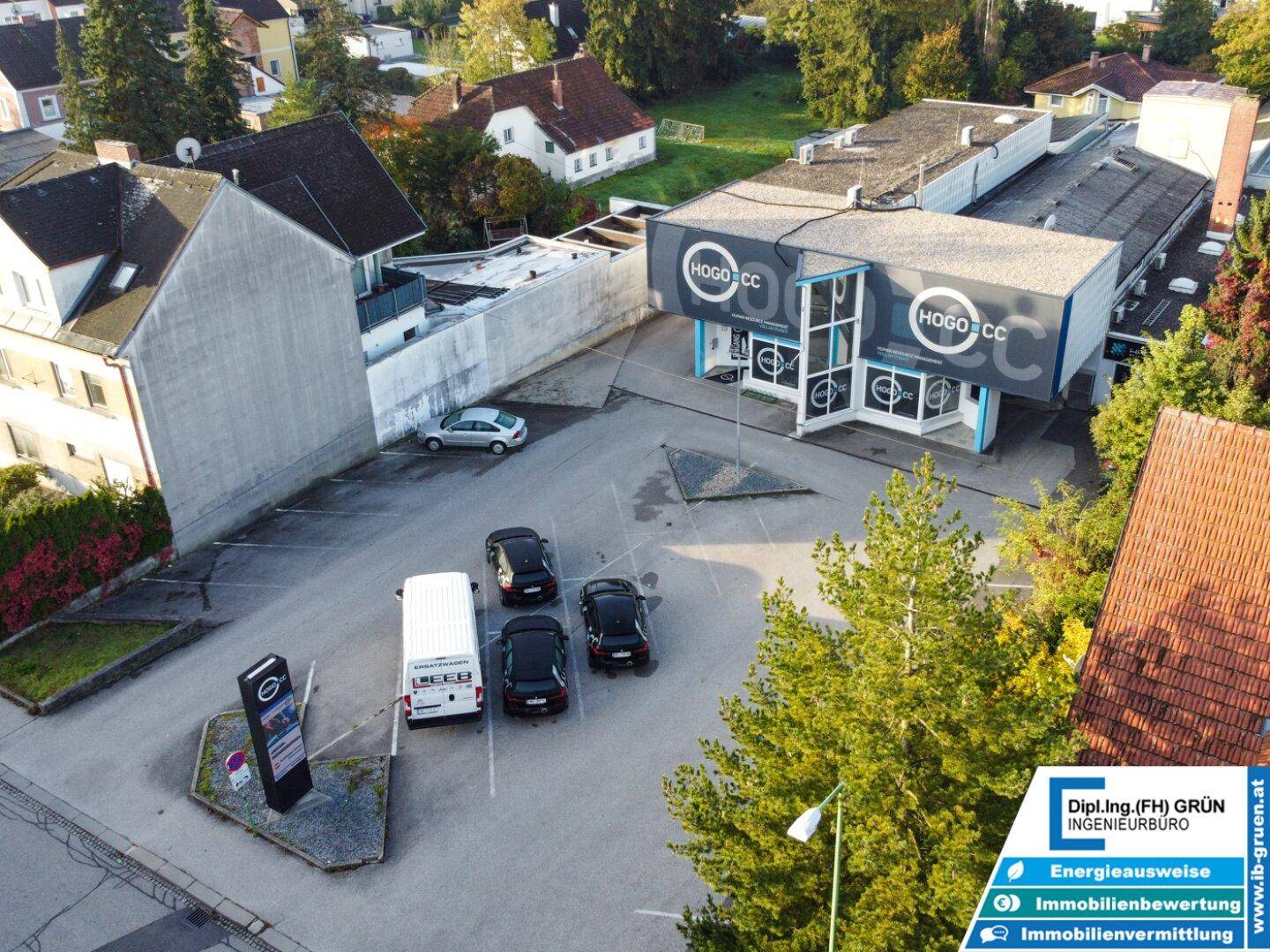 Luftaufnahme des Geschäftsgebäudes mit umliegenden Wohnhäusern und Parkplätzen.