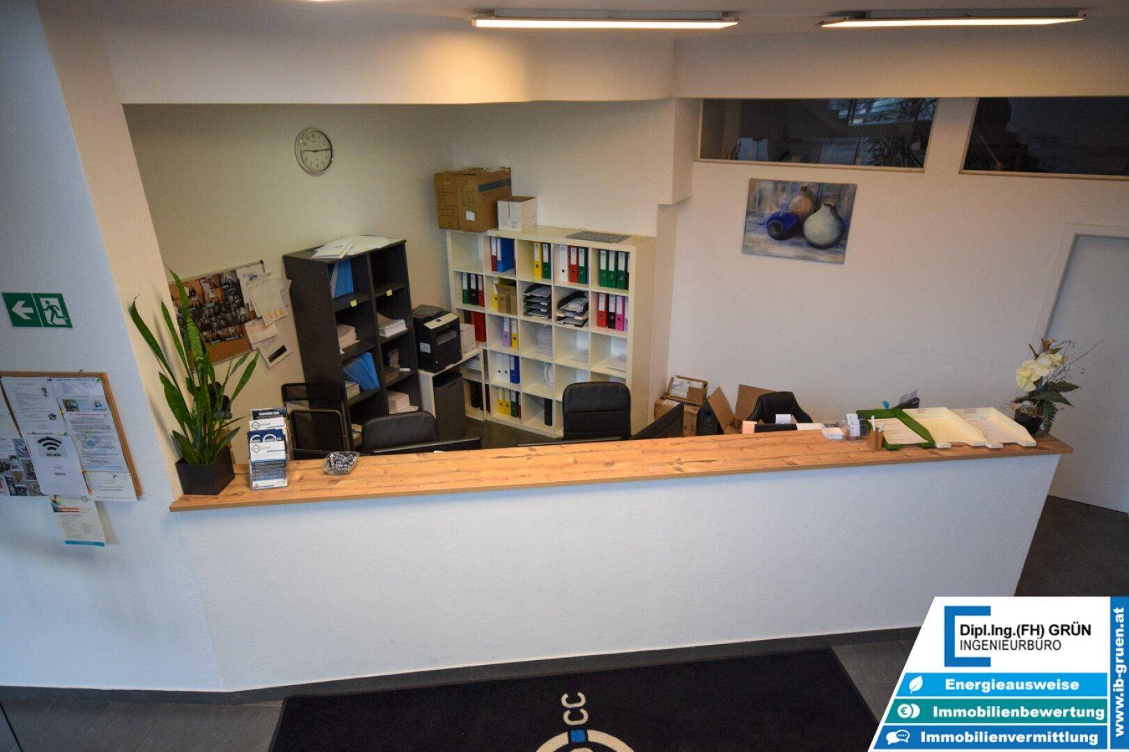 Detailansicht des Empfangstresens mit Holzplatte, Büromaterialien und Ablageflächen.