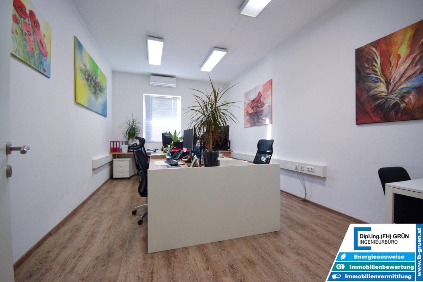 Einzelbüro mit Holzboden, Schreibtischen und farbenfrohen Kunstwerken an den Wänden.