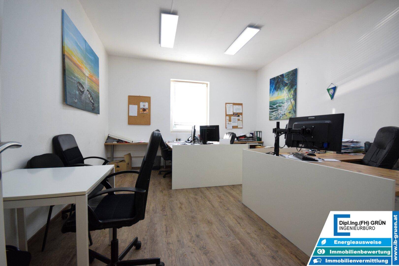 Geräumiges Büro mit mehreren Arbeitsplätzen, Holzboden und natürlichem Lichteinfall.