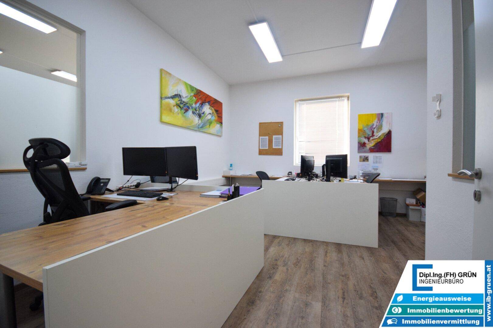 Modernes Büro mit Holzboden, mehreren Arbeitsplätzen und viel Tageslicht.
