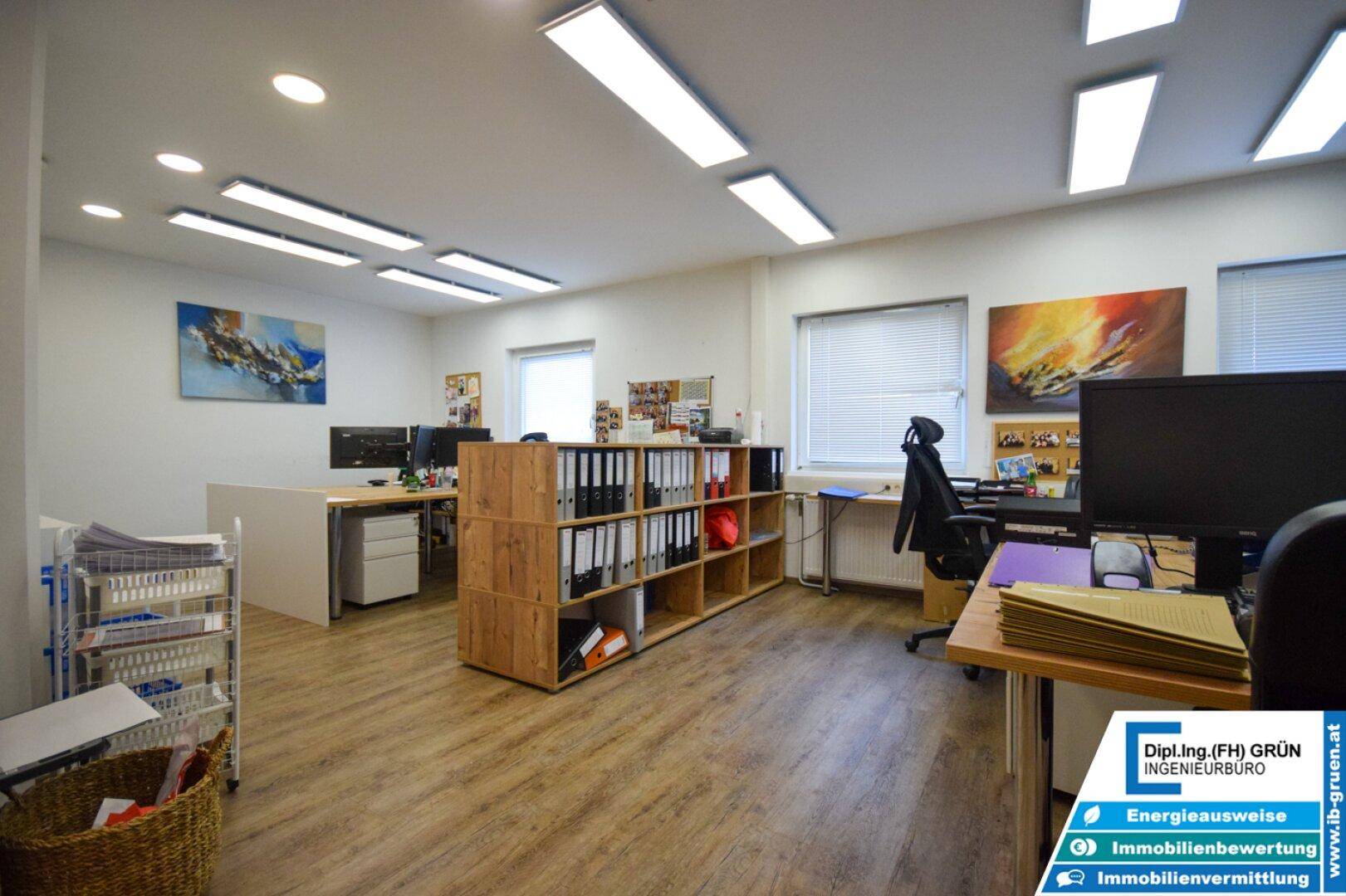Großes Büro mit Holzboden, mehreren Arbeitsplätzen und Regalen für Akten.