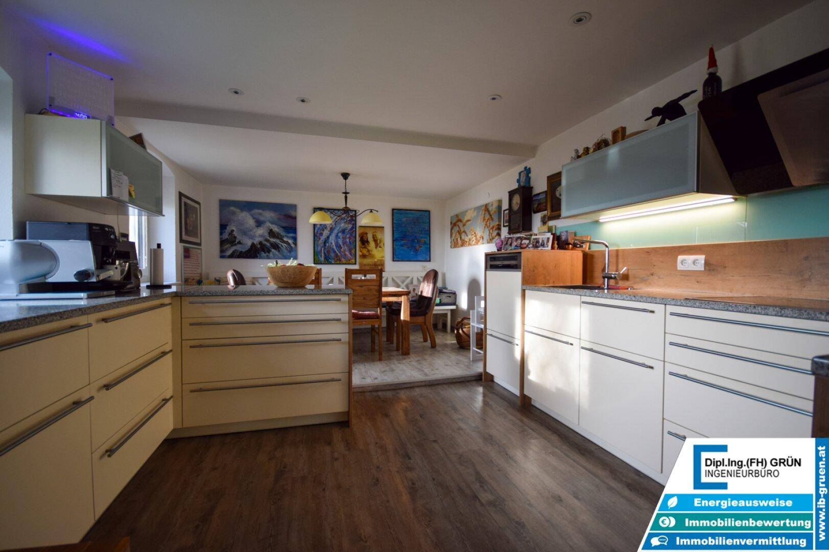 Geräumige Küche mit hellen Schränken, Holztheke und Essbereich im Hintergrund.