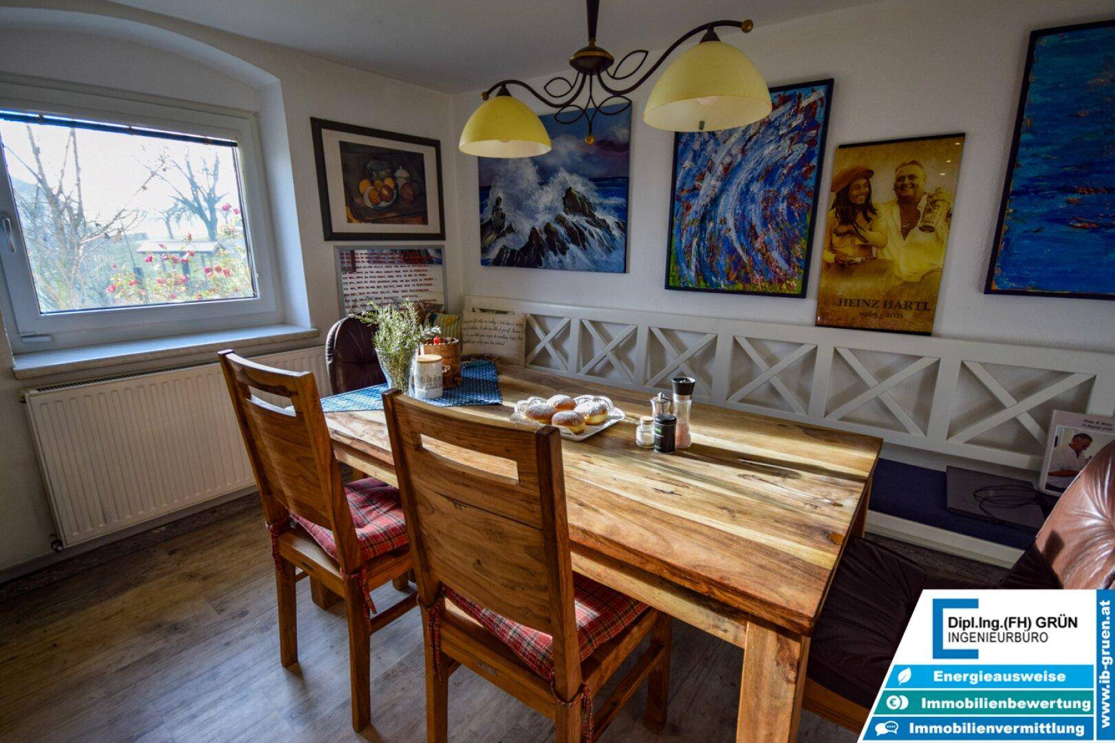 Gemütlicher Essbereich mit Holztisch, Sitzbank und farbenfrohen Bildern an der Wand.
