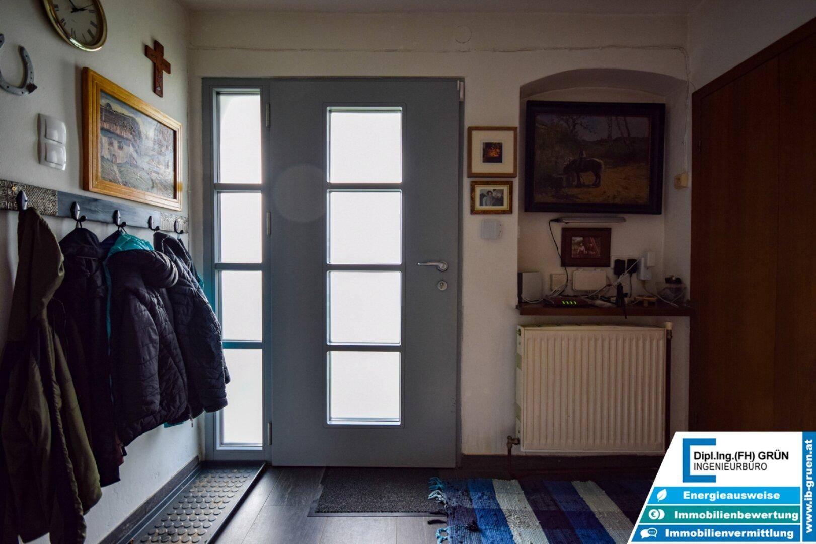 Eingangsbereich mit moderner Haustür, dunklem Fliesenboden und Garderobe.