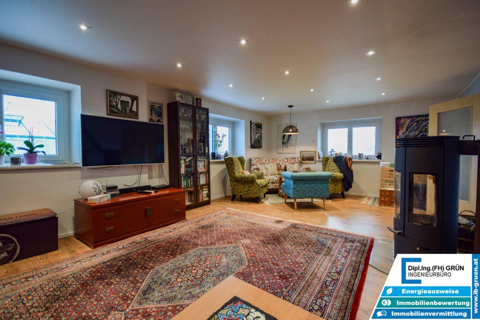 Geräumiges Wohnzimmer mit Holzboden, Kaminofen und gemütlichen Sitzgelegenheiten.