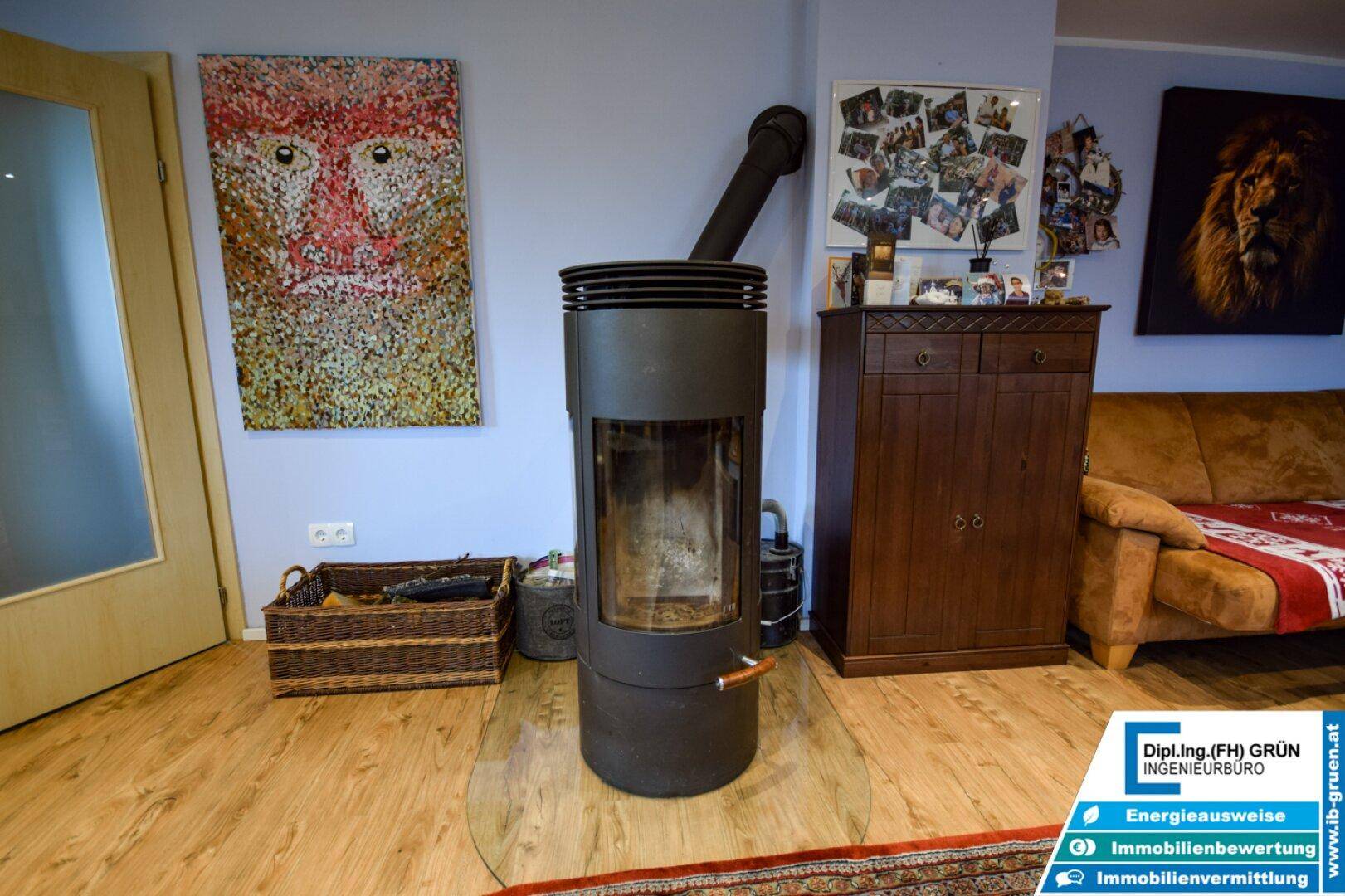 Moderner Kaminofen im Wohnzimmer, umgeben von Holzboden und farbenfrohen Kunstwerken.