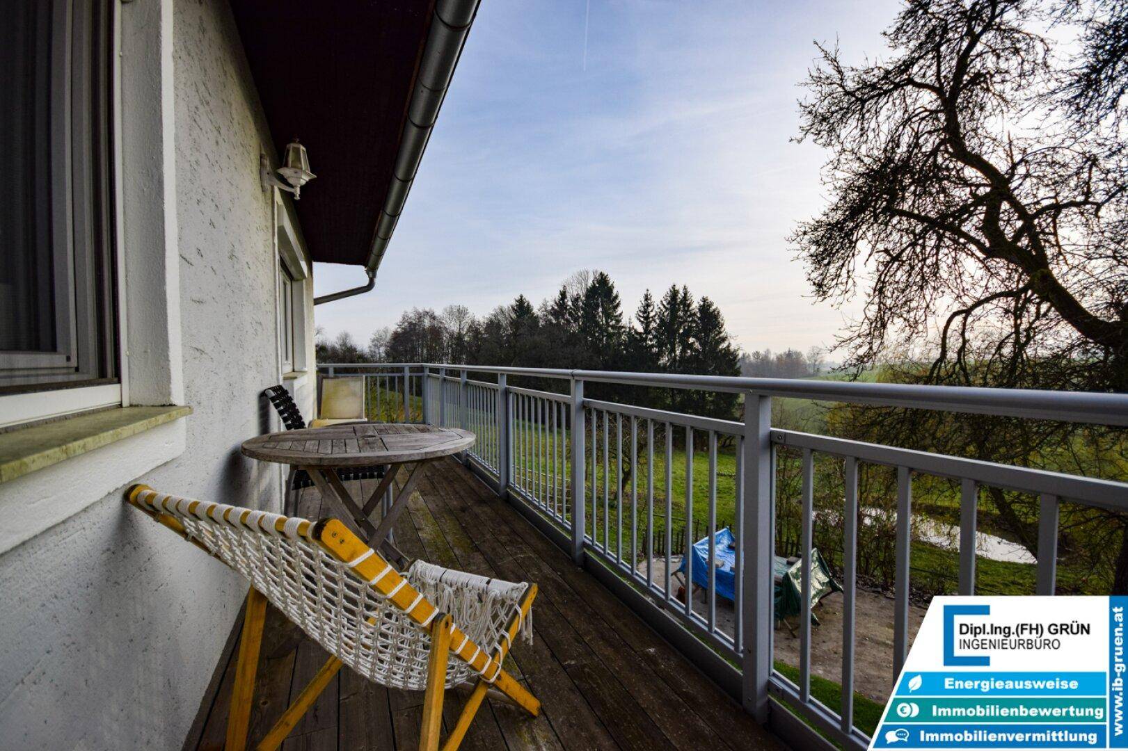 Gemütlicher Balkon mit Holzboden und Blick ins Grüne, ideal für entspannte Stunden im Freien.
