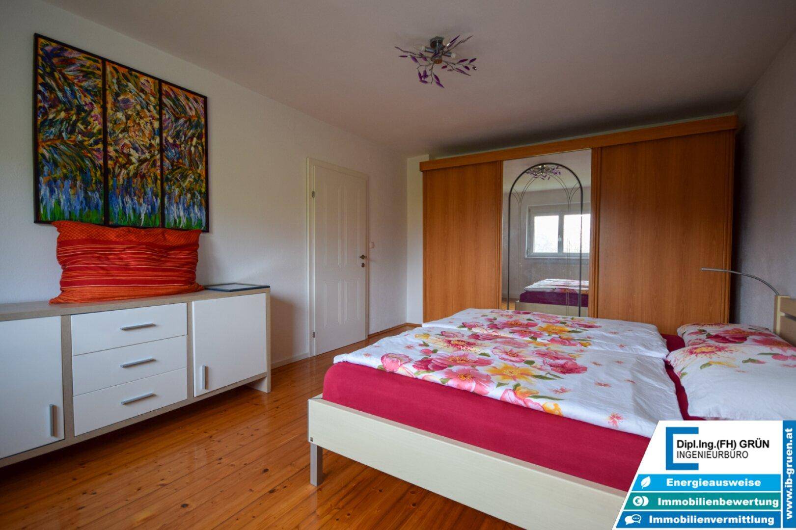 Schlafzimmer mit Holzboden, Kommode und großem Kleiderschrank, bietet ausreichend Stauraum.