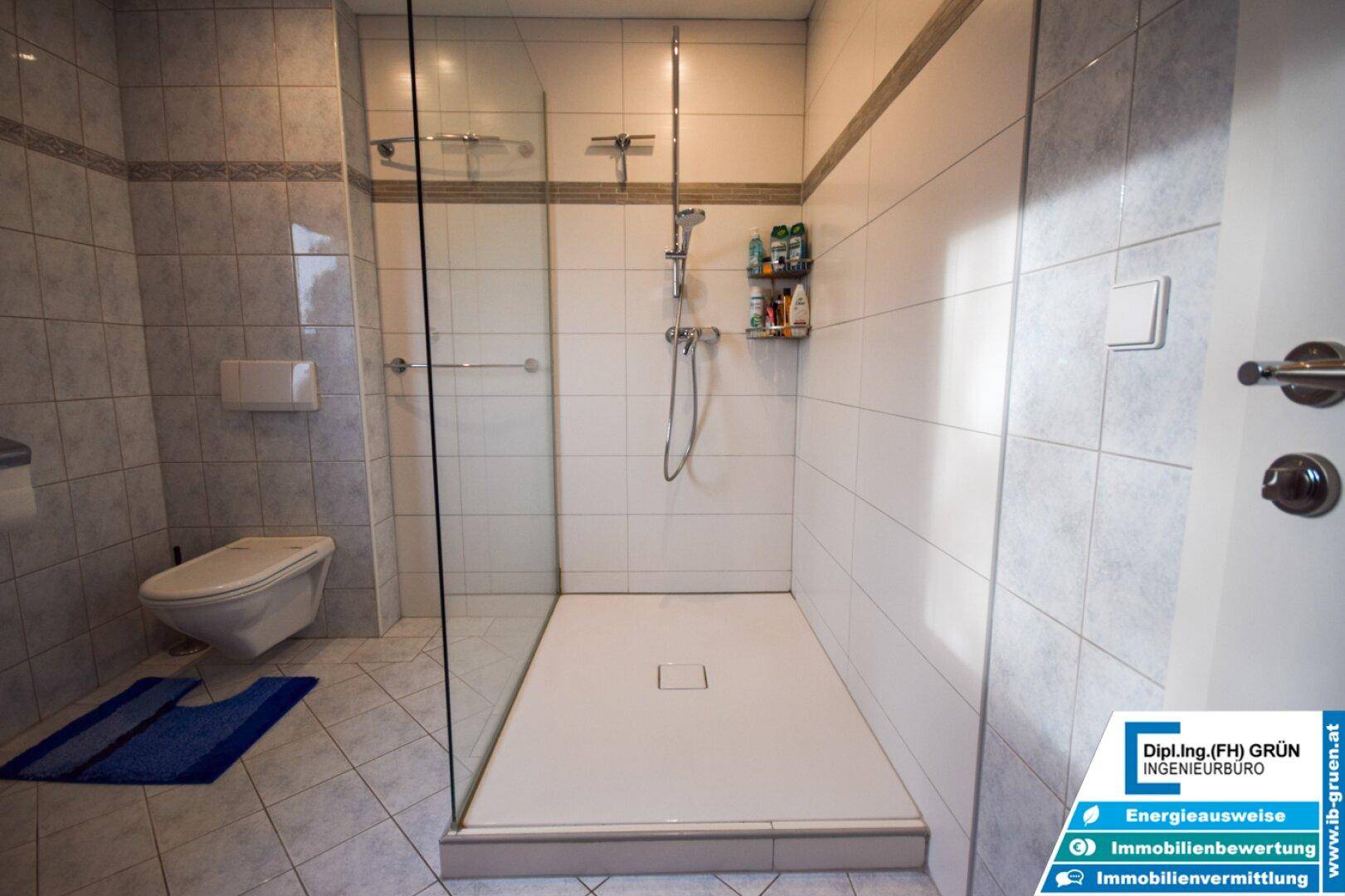 Detaillierte Ansicht der modernen begehbaren Dusche und des wandhängenden WCs im Badezimmer.