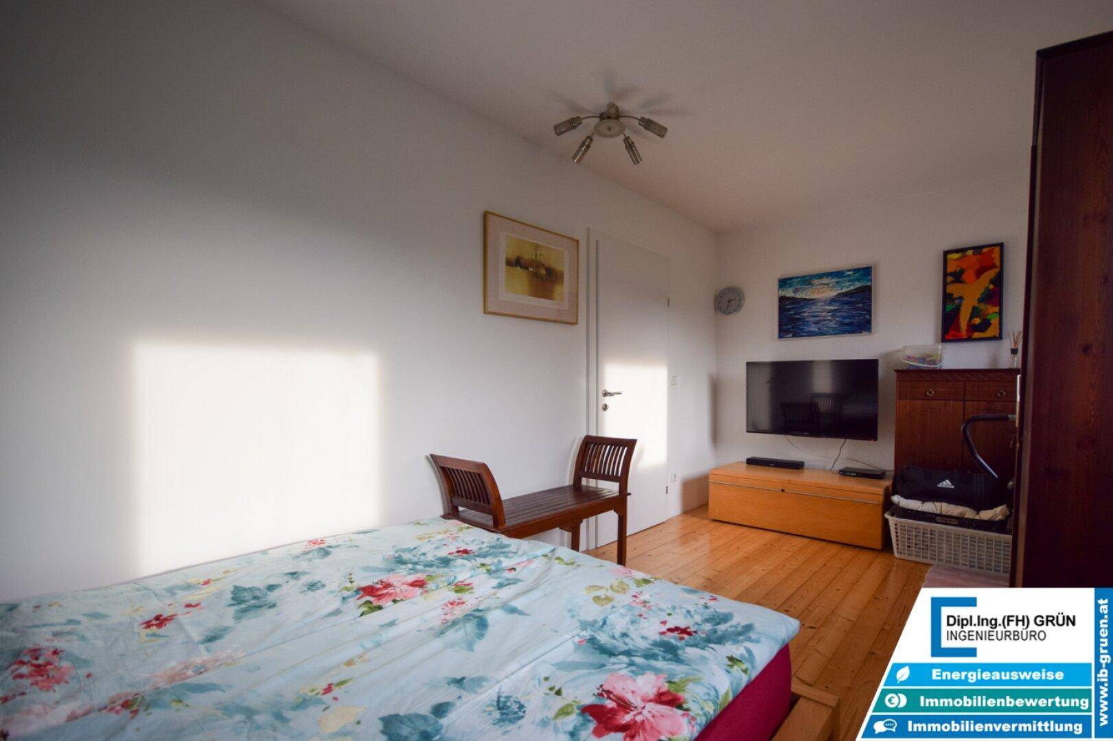 Schlafzimmer mit Holzboden, Fernseher und Sitzbank, bietet Komfort und Unterhaltung.