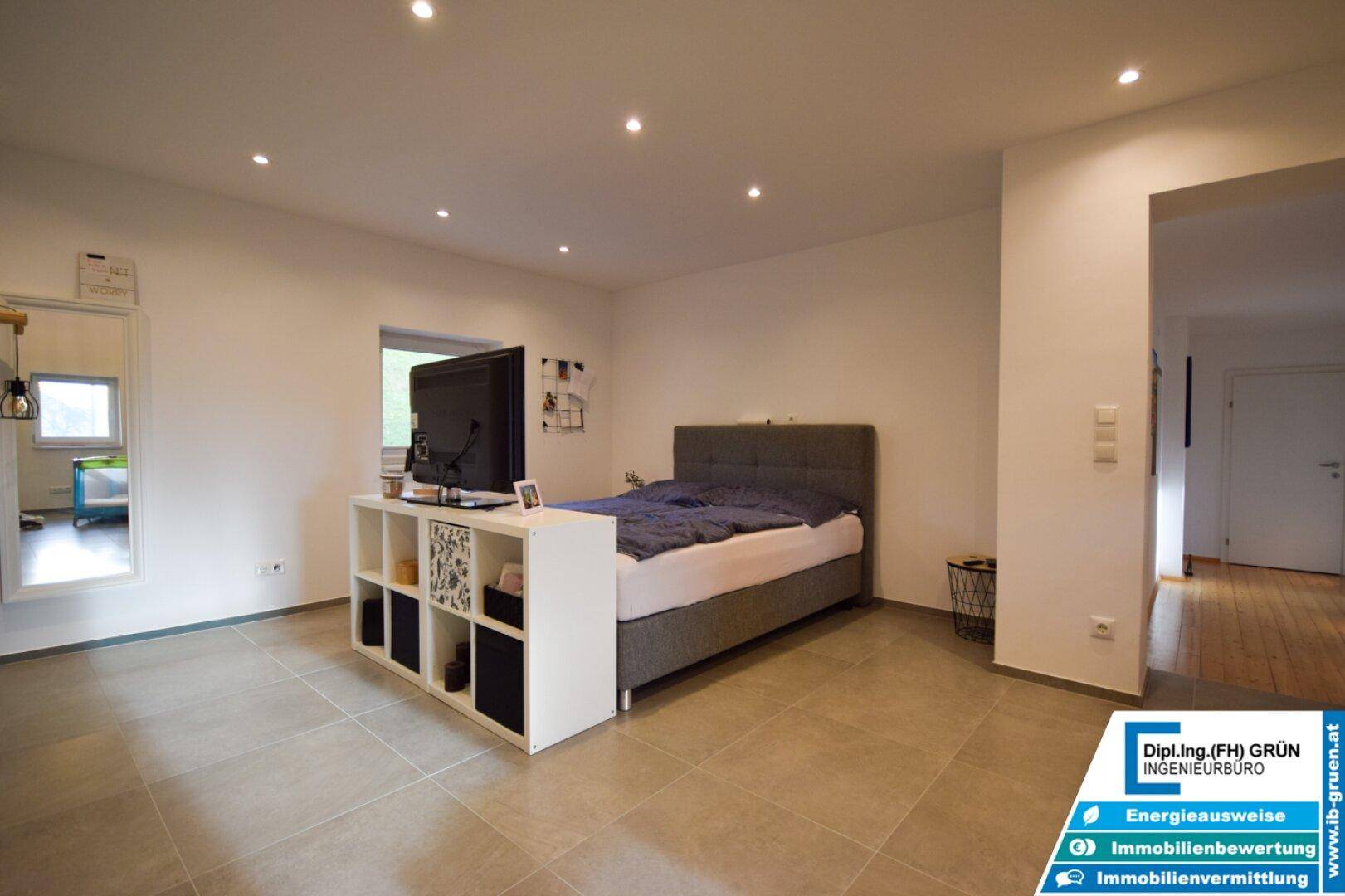 Modernes Schlafzimmer mit grauen Fliesen, Bett und integrierter Beleuchtung, bietet eine schlichte Eleganz.