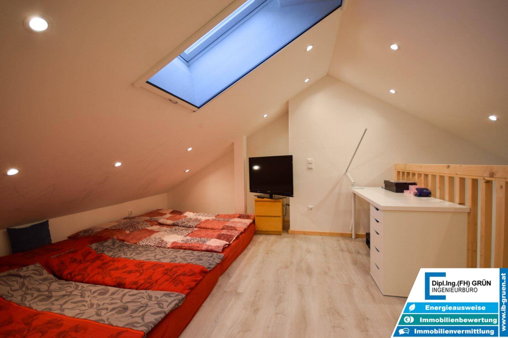 Gemütlicher Dachbodenbereich mit Bett, Schreibtisch und Dachfenster, ideal als zusätzliches Schlafzimmer.