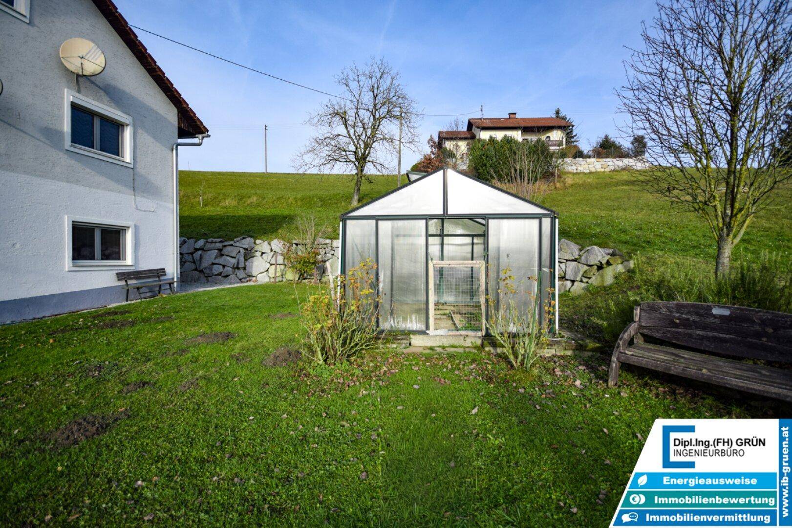 Kleines Gewächshaus im grünen Garten, ideal für den Anbau von Pflanzen und Gemüse.