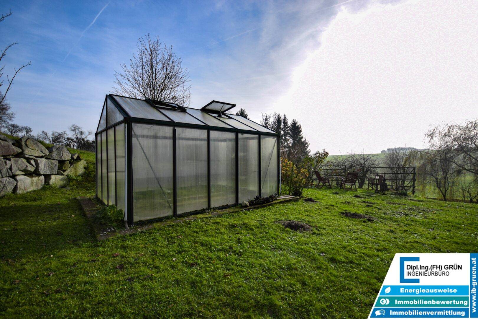 Gewächshaus im Garten, umgeben von Grünflächen, bietet optimale Bedingungen für die Pflanzenzucht.