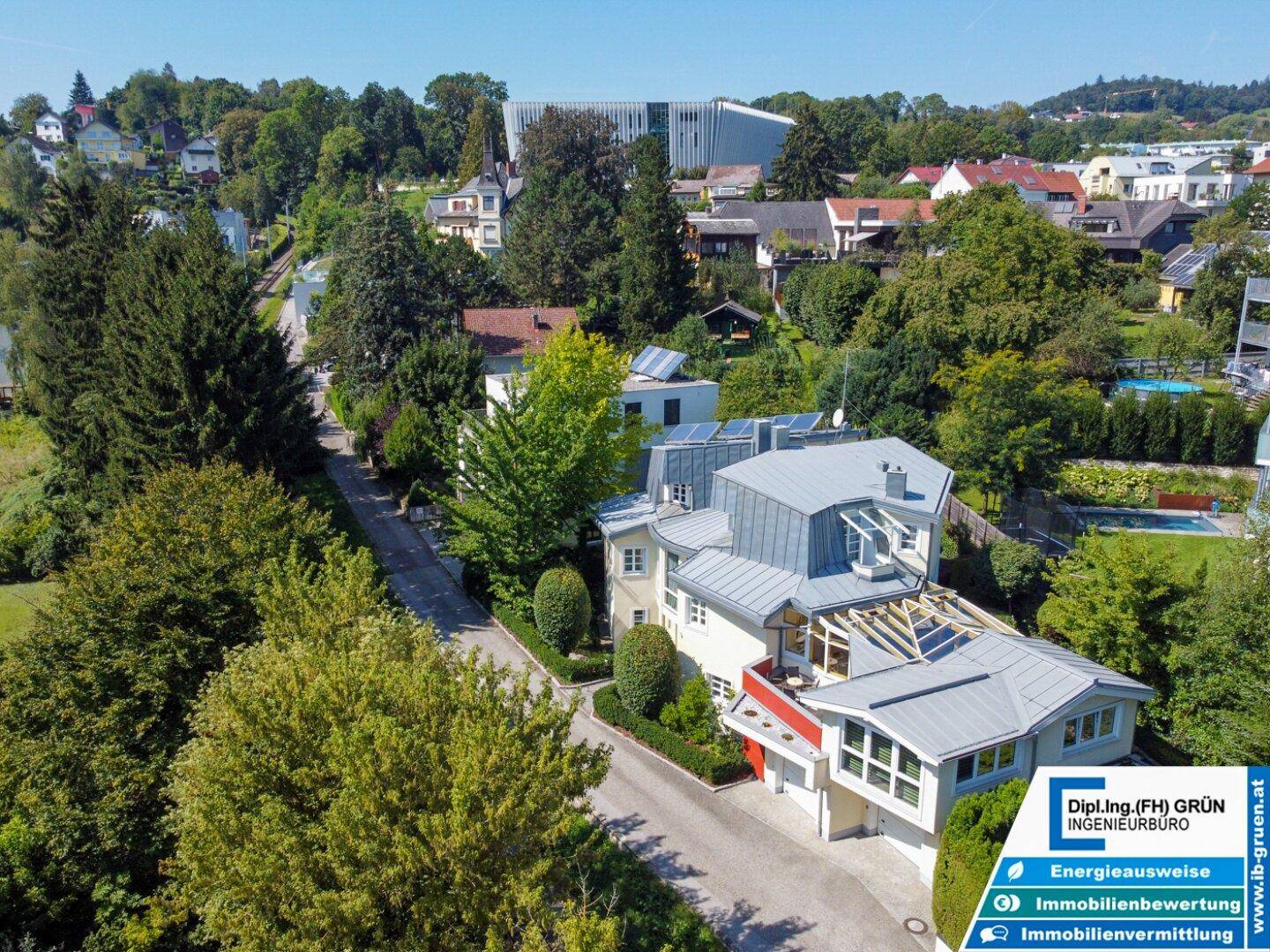 Luftaufnahme des Anwesens mit weitläufigem Garten, umgeben von Bäumen und Wohnbebauung in einer grünen Umgebung.