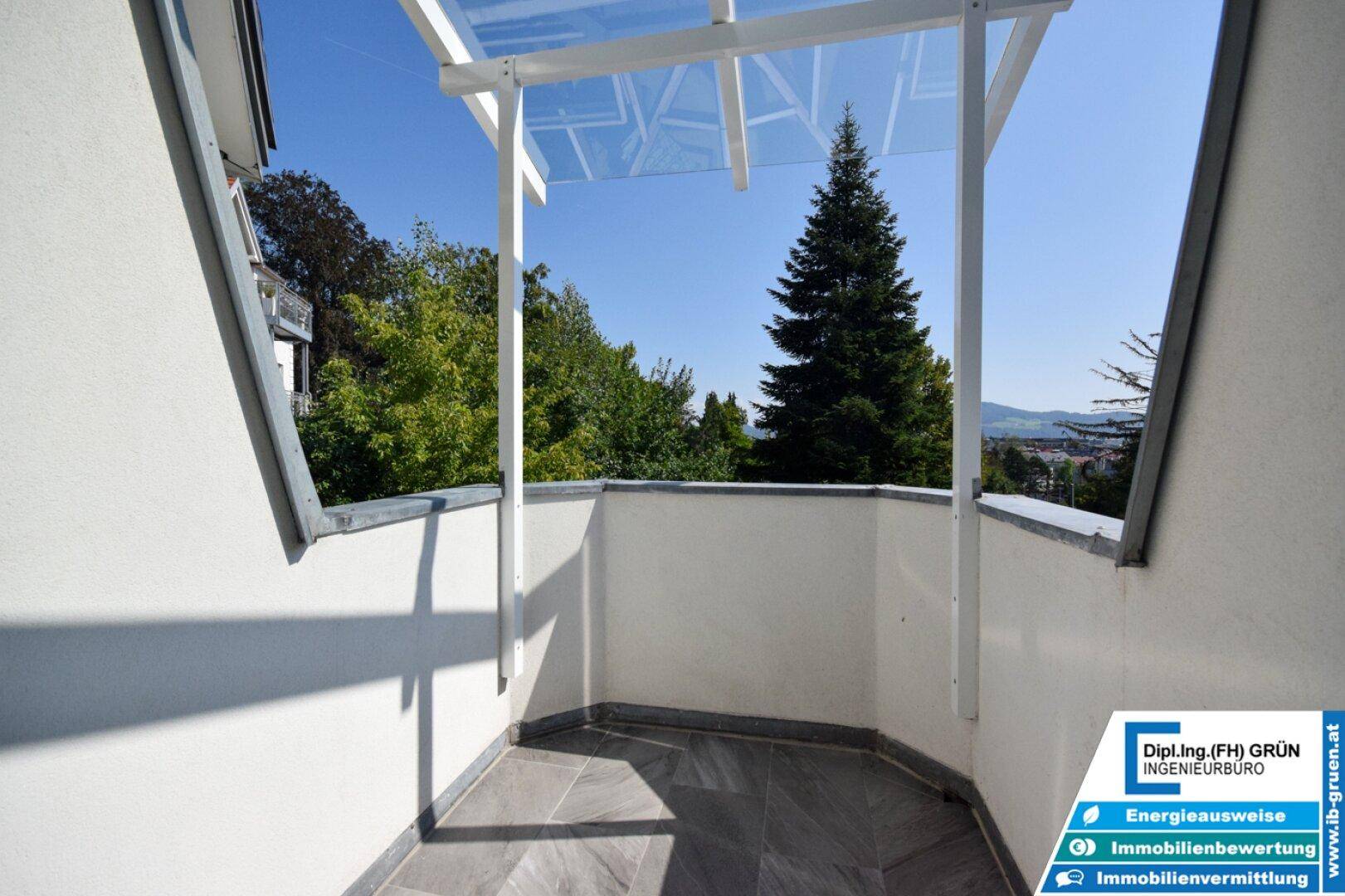 Kleiner Balkon mit Fliesenboden und Glasüberdachung, bietet einen Blick ins Grüne.