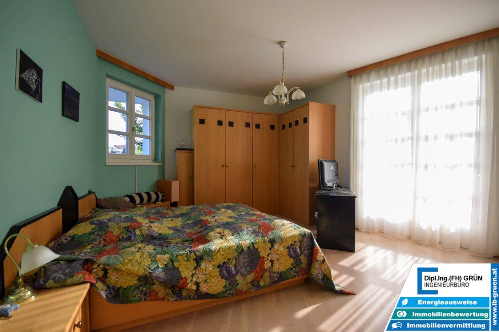 Helles Schlafzimmer mit mintgrünen Wänden, Holzboden und großem Kleiderschrank.