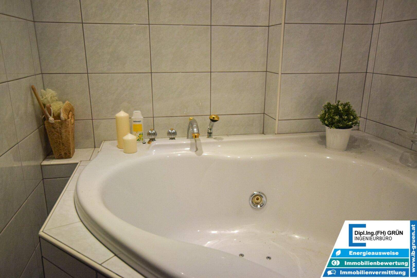 Badezimmer mit Eckbadewanne, weißen Fliesen und dekorativen Kerzen für eine entspannende Atmosphäre.