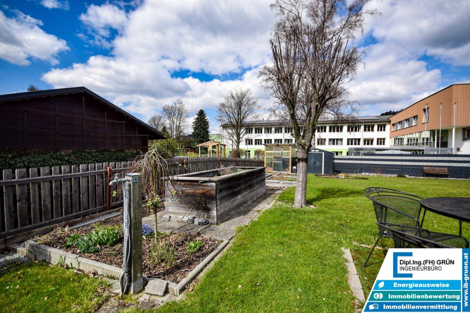 Hochbeete im Gartenbereich mit Wasseranschluss und Blick auf die umliegenden Gebäude.