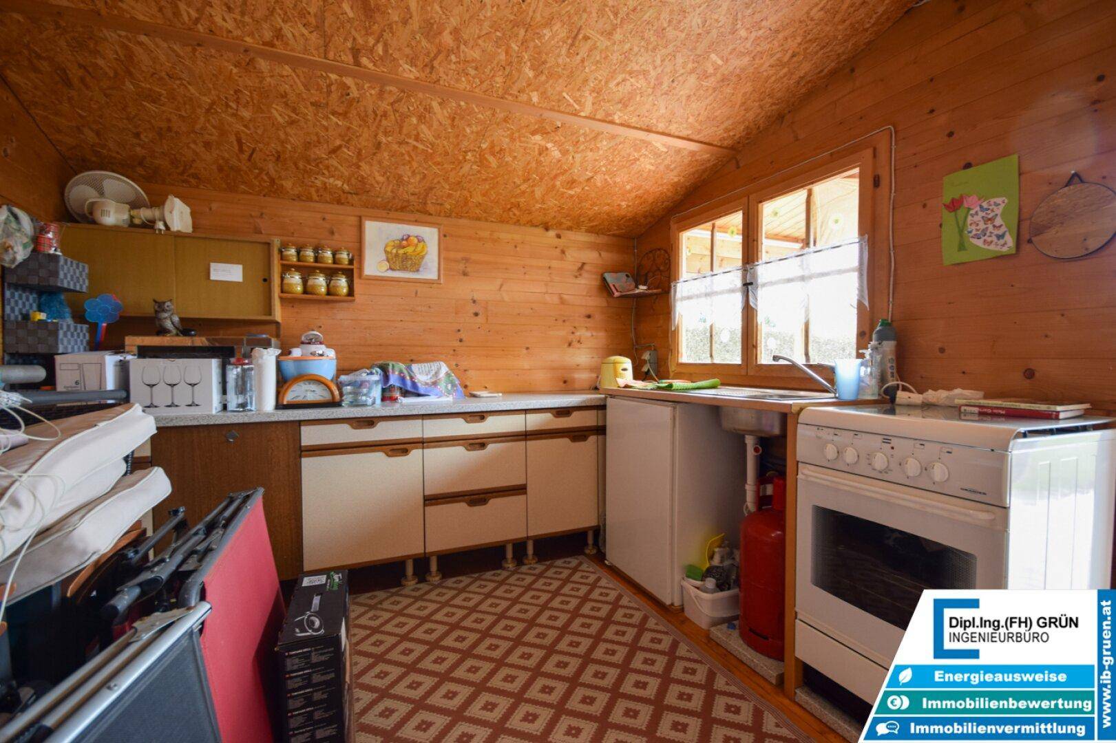 Rustikale Küche im Gartenhaus mit Holzverkleidung, Gasherd und einfacher Ausstattung.