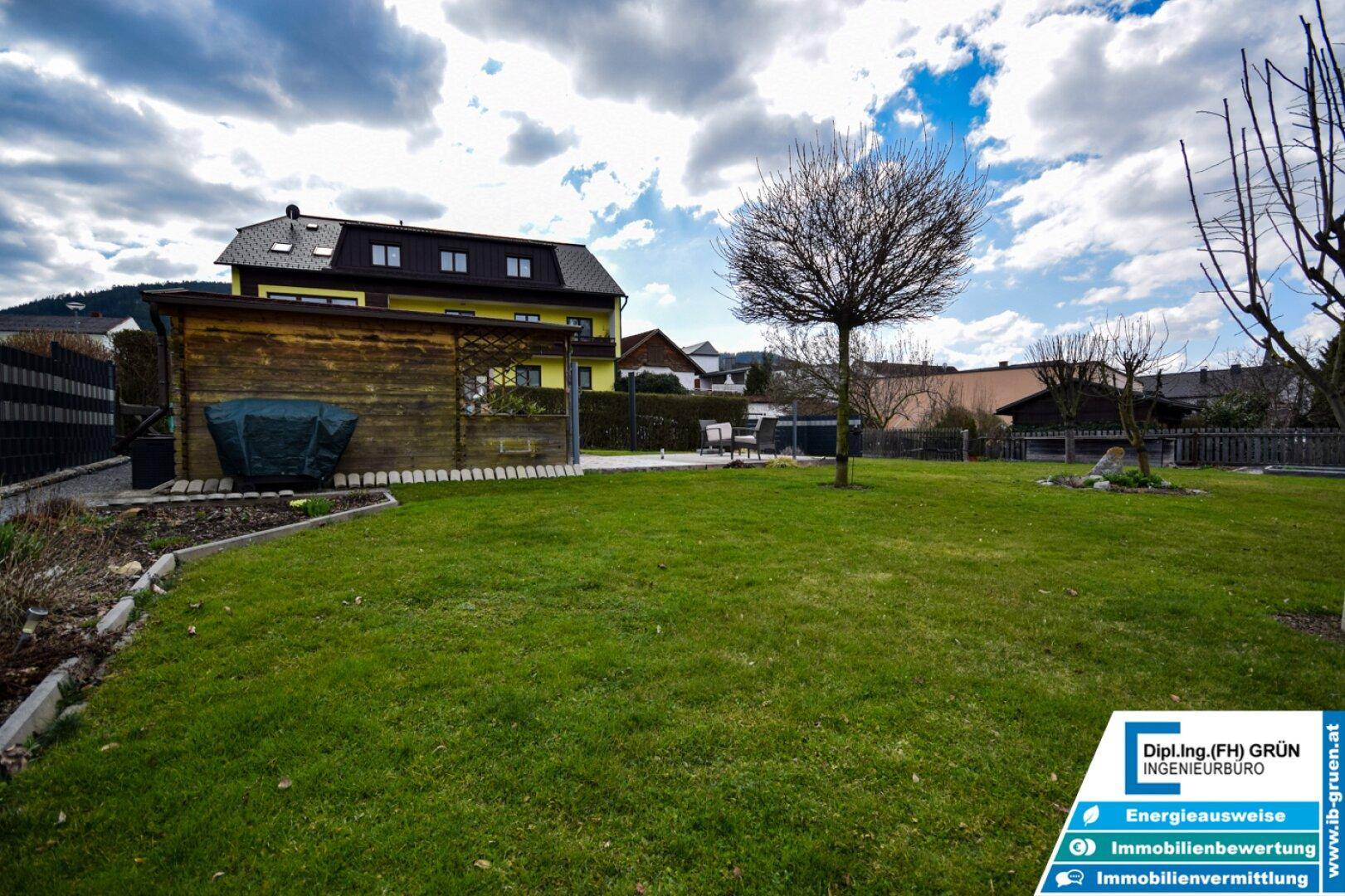 Weitläufiger Garten mit Rasenfläche und Blick auf das angrenzende Wohnhaus und die Umgebung.