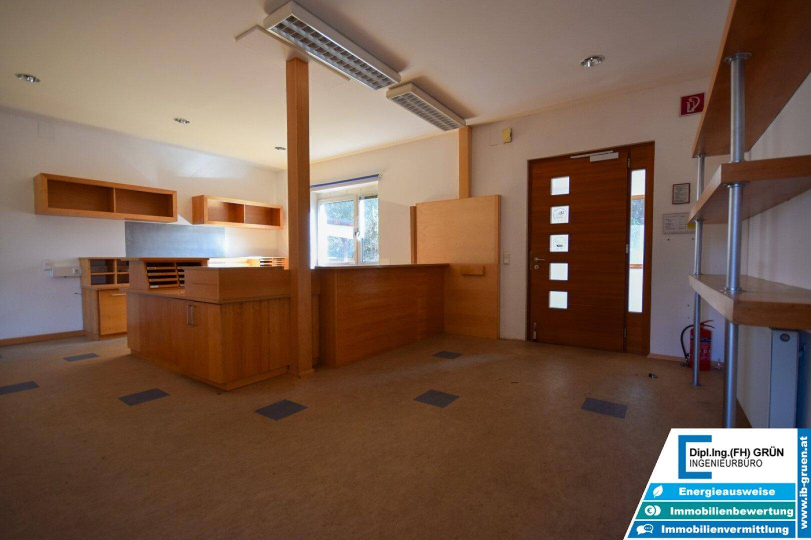 Empfangsbereich oder Büro mit Holzmöbeln, Regalen und Linoleumboden, gut beleuchtet durch Fenster.