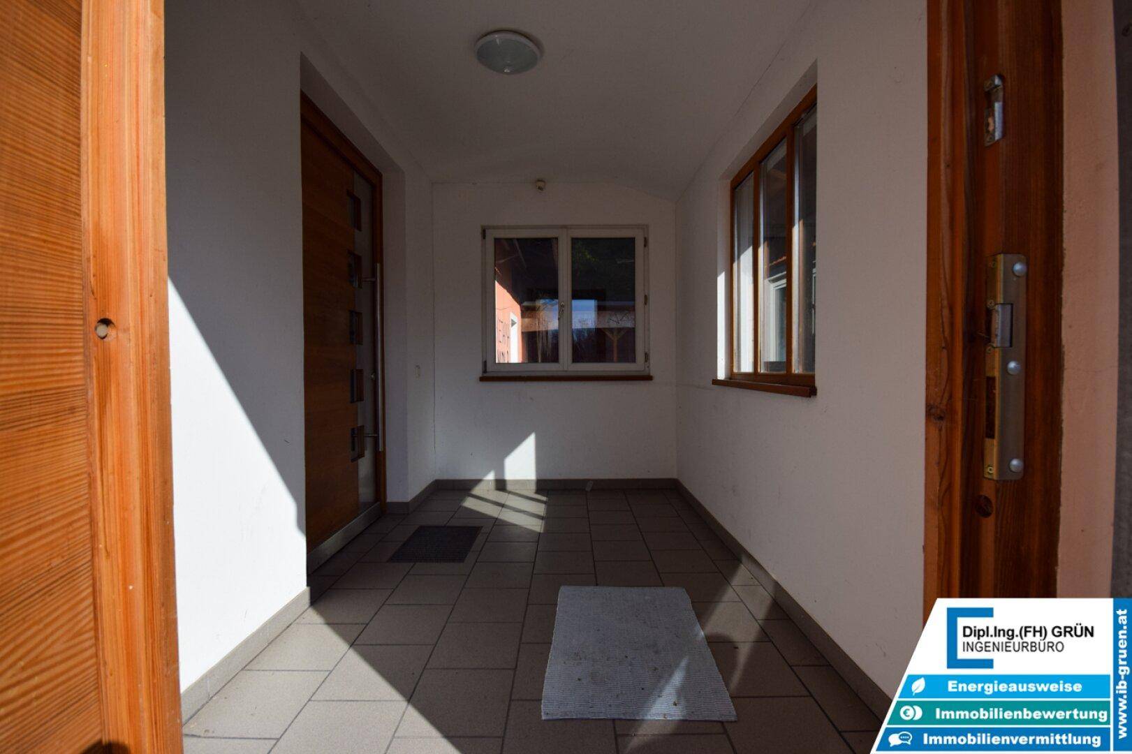 Heller Eingangsbereich oder Flur mit Fliesenboden und Holztüren, durch Fenster natürlich belichtet.