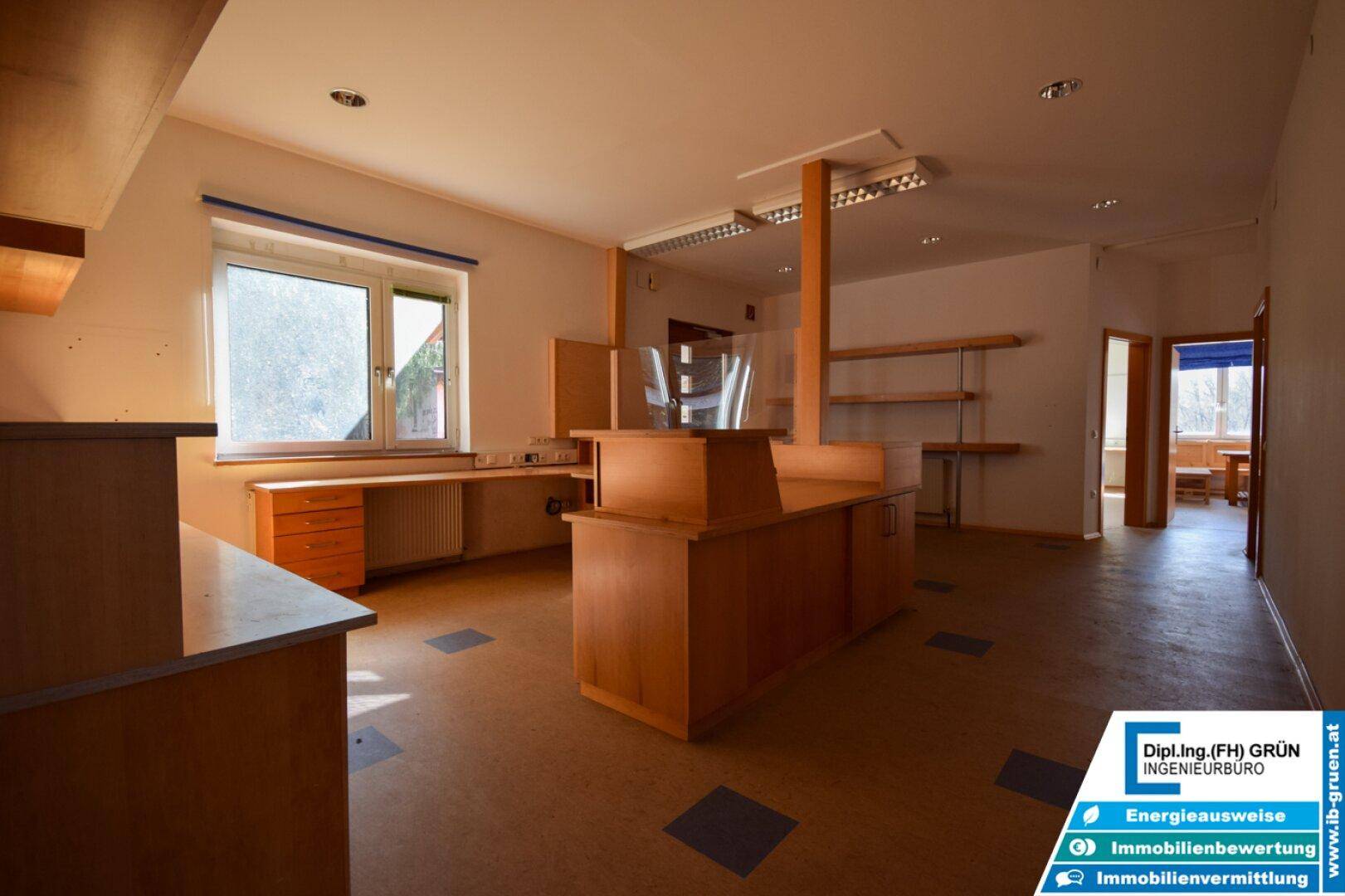 Geräumiger Büro- oder Empfangsbereich mit Holzmöbeln, Regalen und Linoleumboden, hell und funktional.