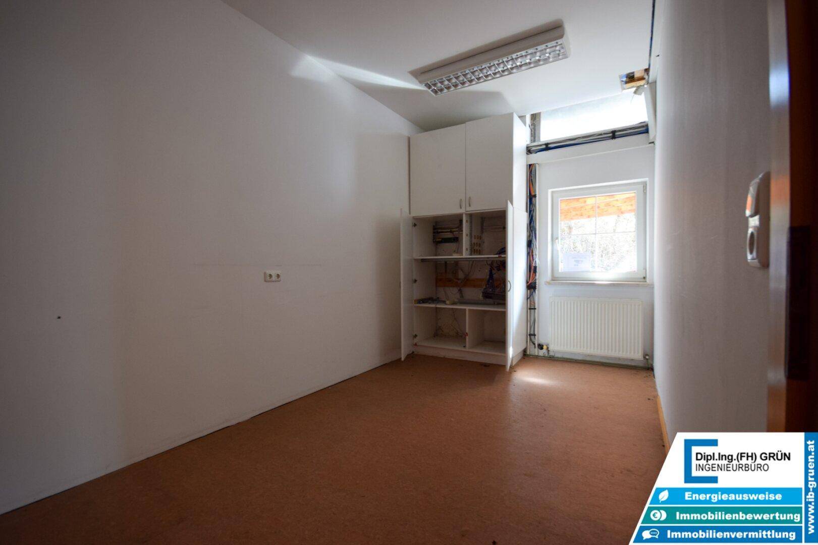 Lagerraum mit Regalen, einem Fenster und einfacher Beleuchtung, ideal für Abstellzwecke.