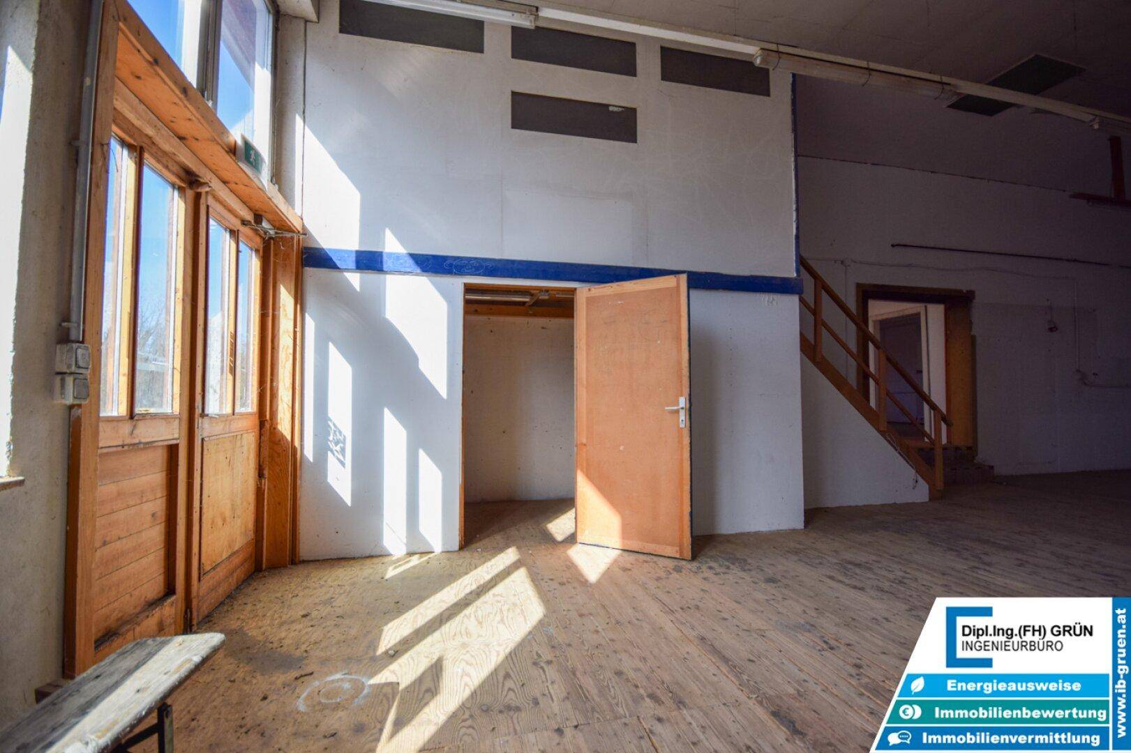 Heller Lagerraum mit Holztüren, hohen Decken und natürlichem Lichteinfall durch große Fenster.