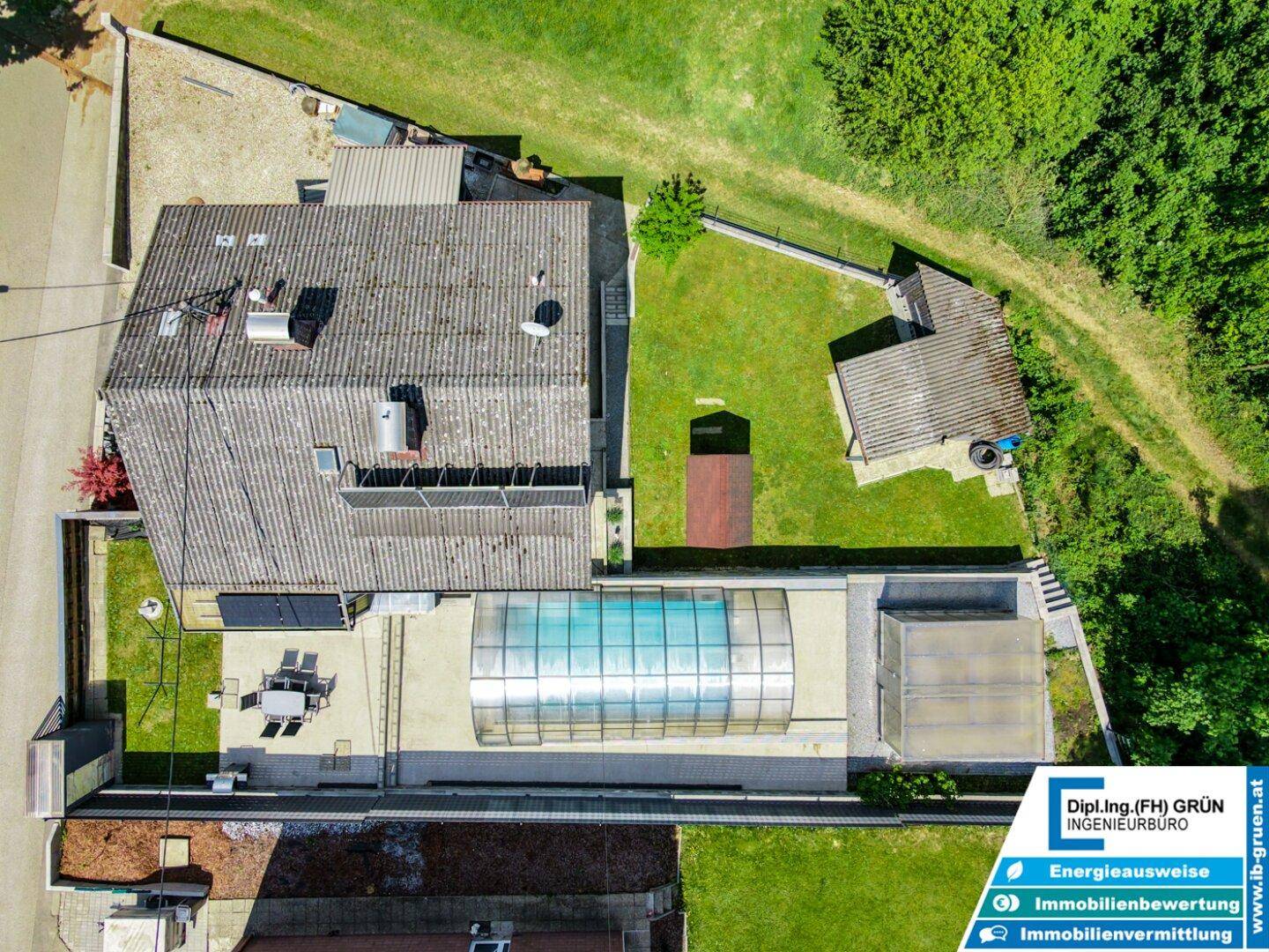Luftaufnahme des Anwesens mit Haus, Poolbereich, Garten und Photovoltaikanlage auf dem Dach.