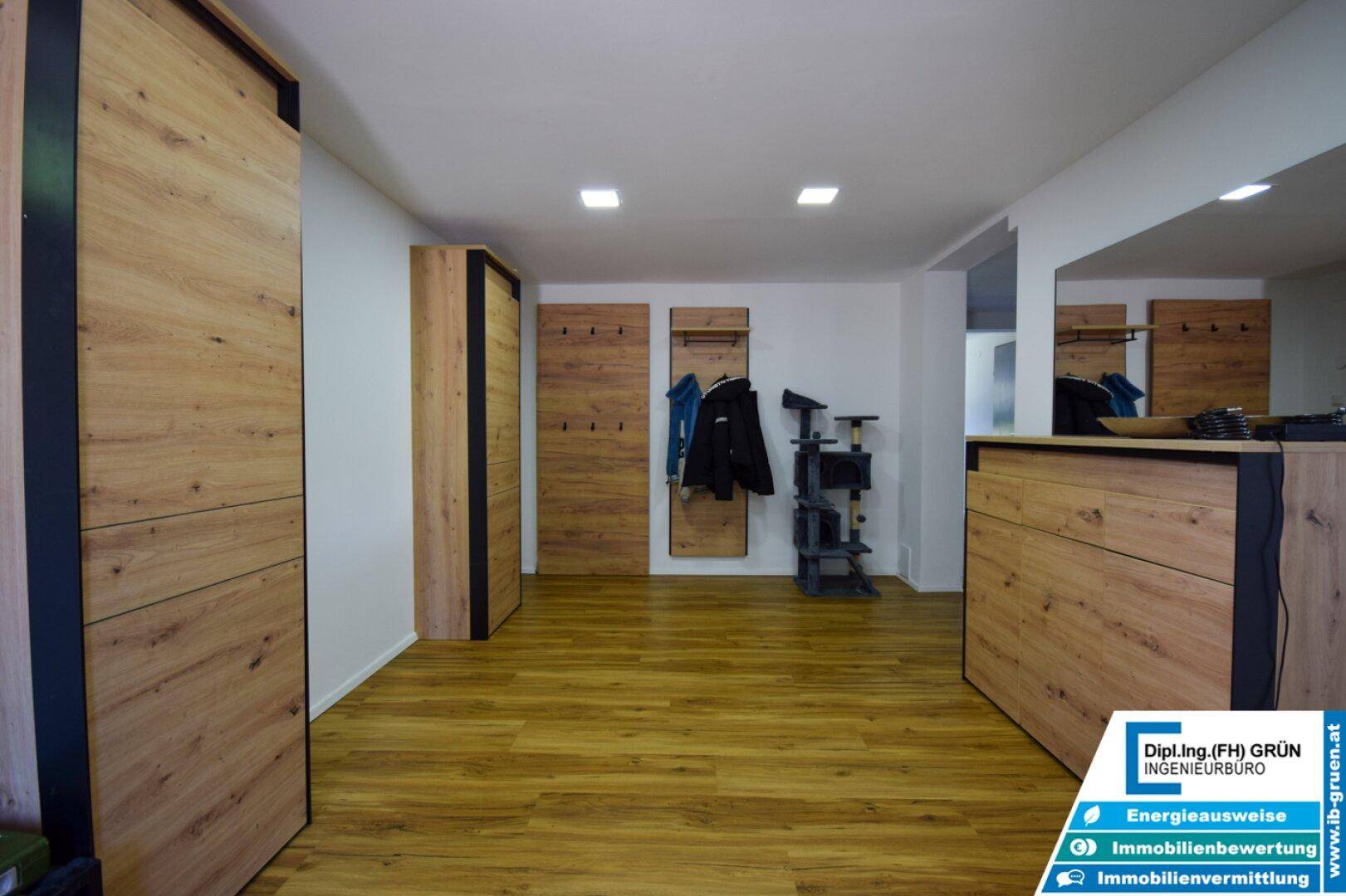 Geräumiger Eingangsbereich mit Holzfußboden und modernen Garderobenschränken in Holzoptik.